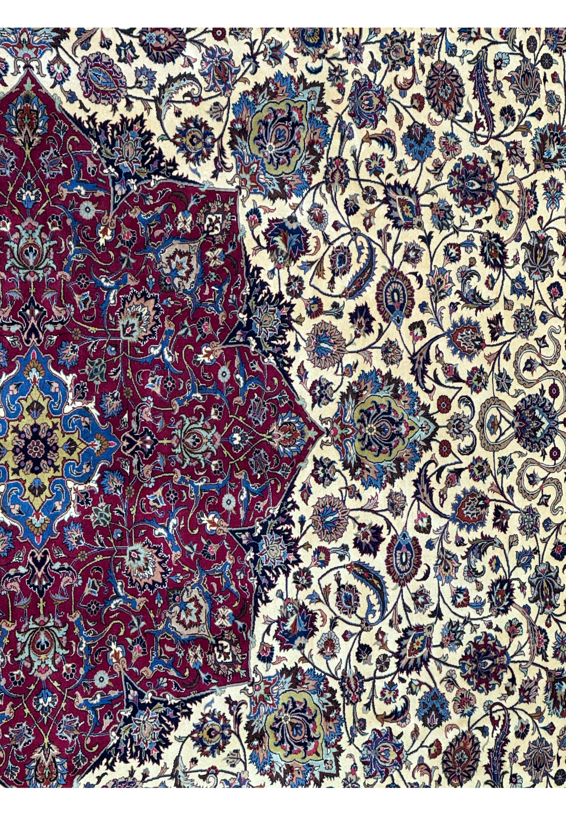 Close-up view of the right border and part of the central medallion of a Persian Mashad rug, featuring detailed floral and vine designs in red, blue, and beige, demonstrating the rug's exquisite craftsmanship.
