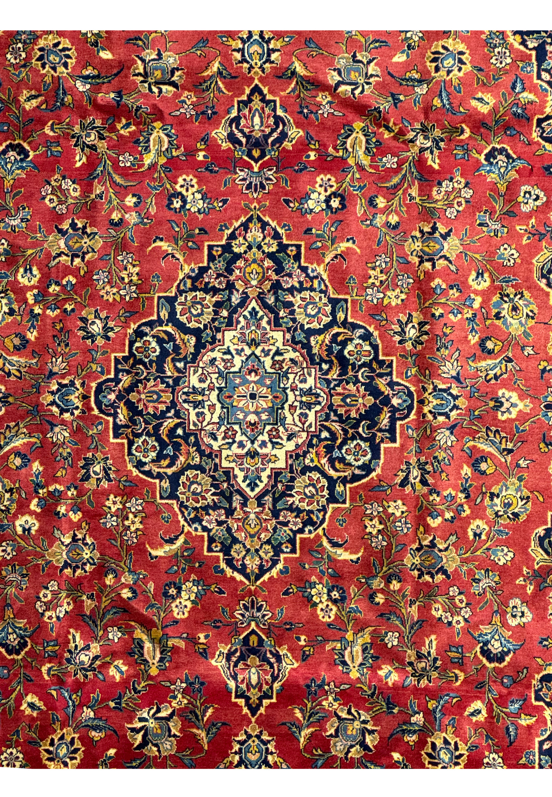 Close-up of the border of a Persian Kashan rug, showcasing the intricate floral patterns and detailed weaving. The border's design complements the central field with repeating motifs in blue, gold, and ivory on a dark background. This image highlights the meticulous craftsmanship and high knot density that define the quality of Kashan rugs. The rich colors and detailed patterns add a touch of elegance to any room.