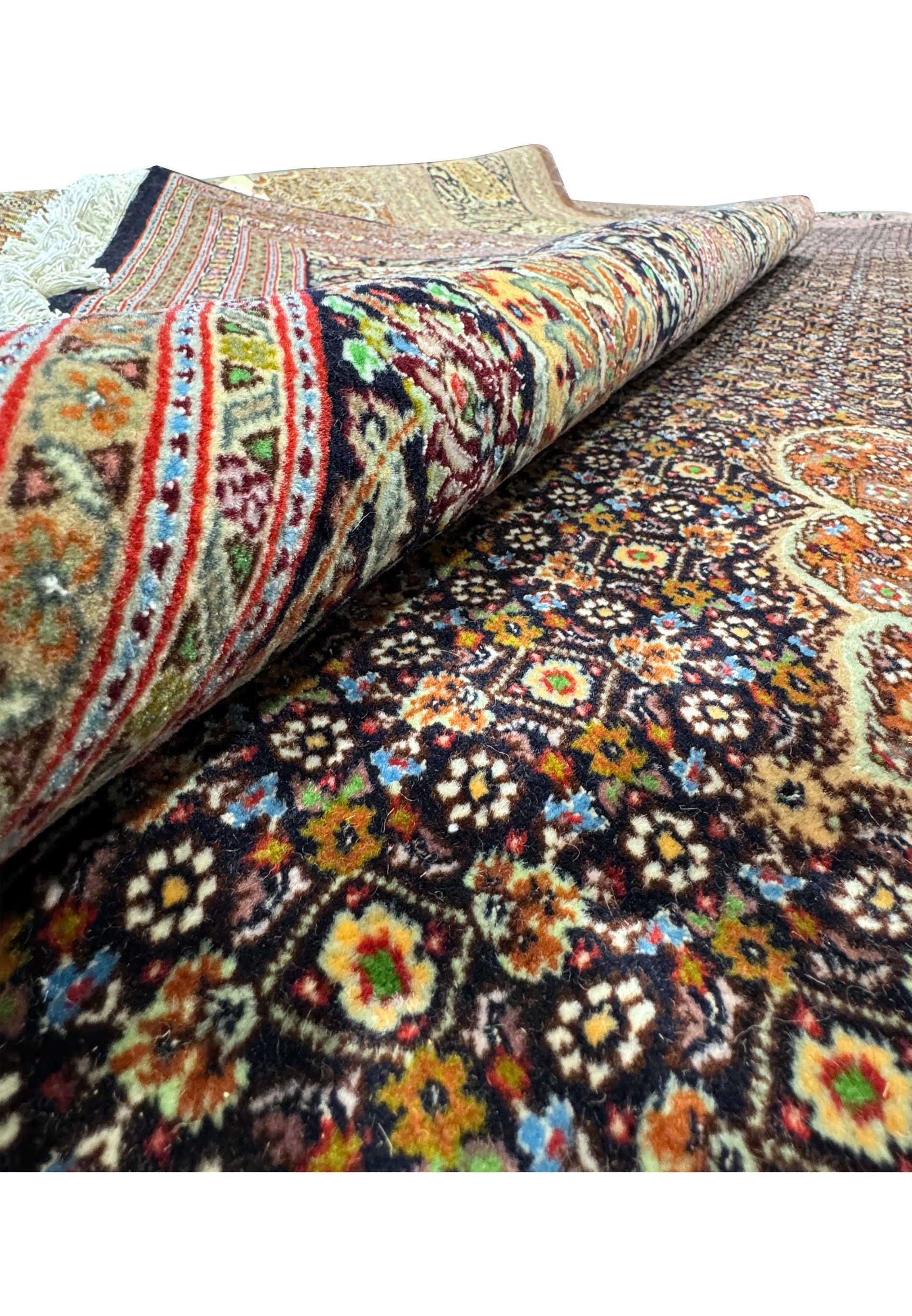 Close-up view of a 11'7 x 16'6 Persian Tabriz Mahi 50 Raj rug rolled to showcase the intricate floral and geometric patterns in vibrant colors, highlighting the detailed craftsmanship and premium quality wool and silk materials used in this exquisite handmade rug