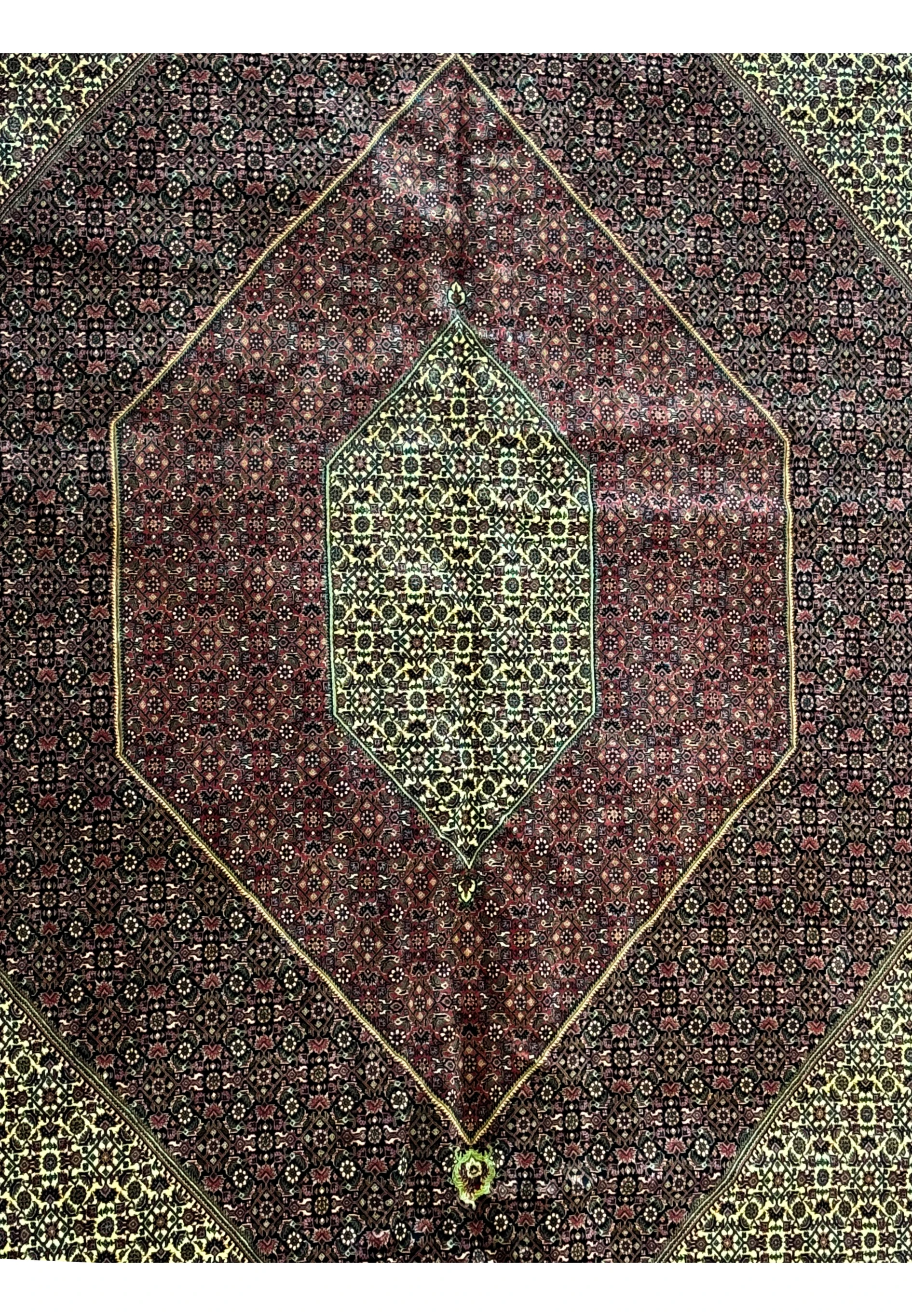 Close-up of the central medallion on a Persian Bijar Rug with rich red and gold hues.