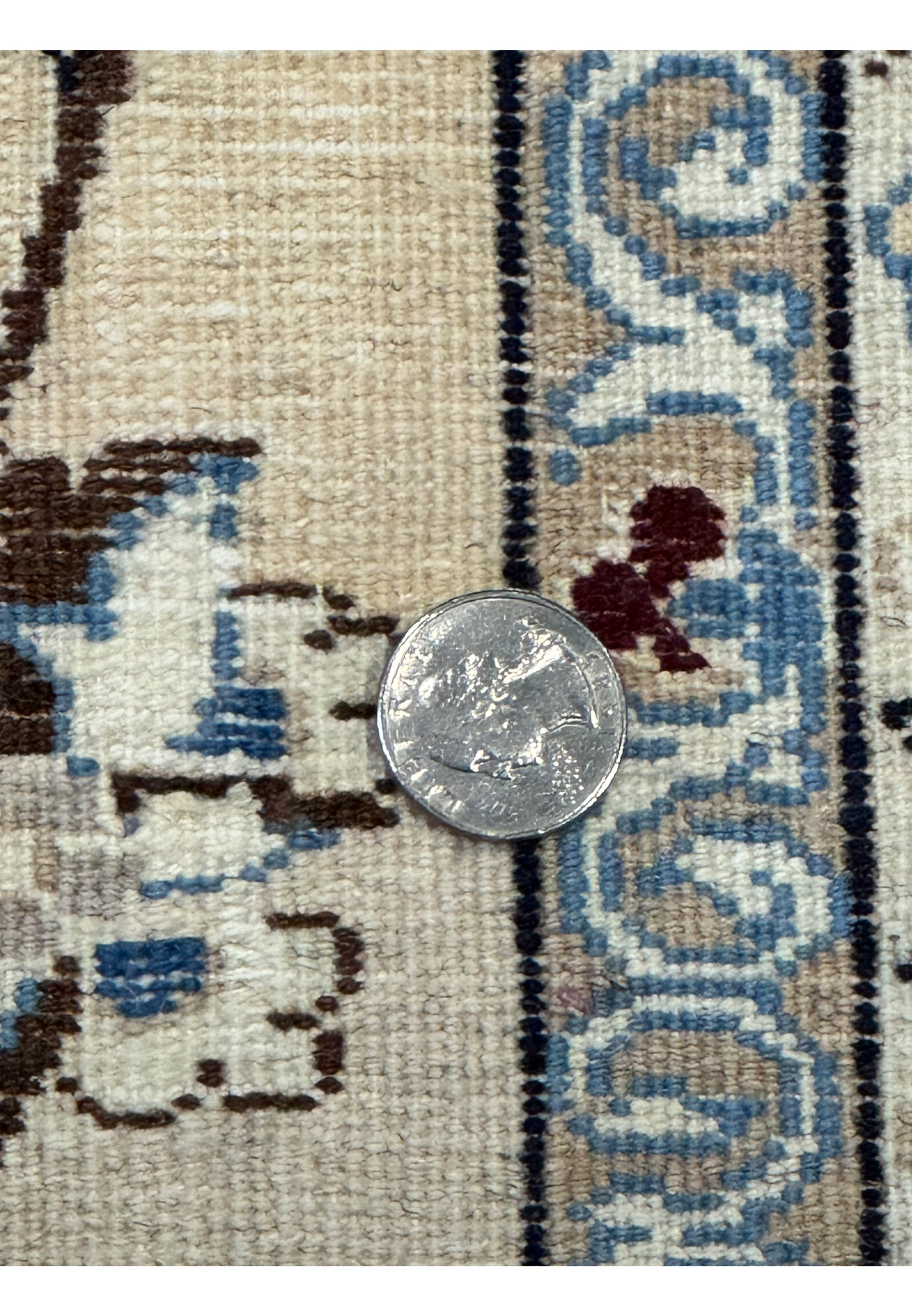 Close-up of a coin placed on the backside of the Persian Nain 9LAA Wool & Silk Rug showing the weave.