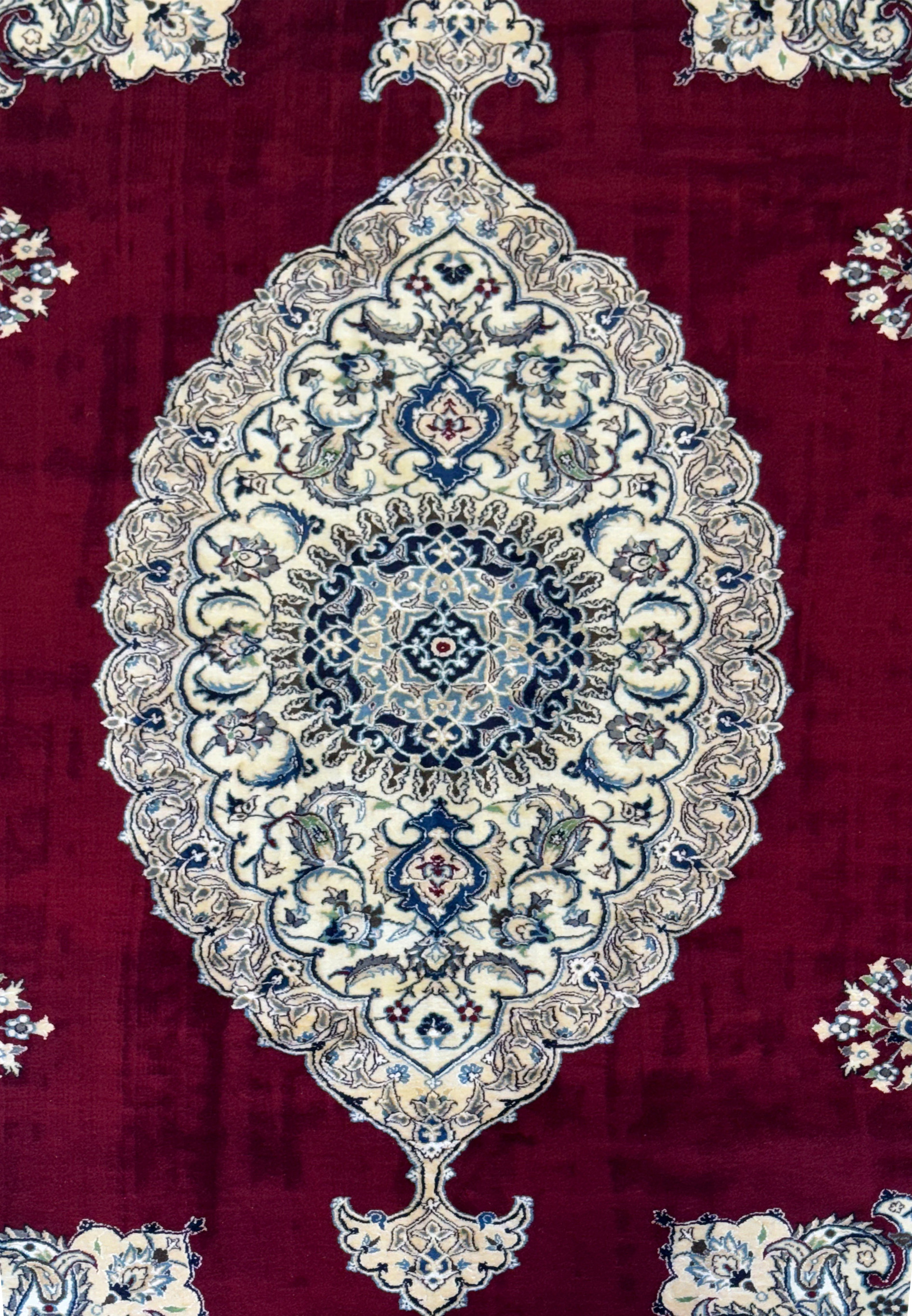 Close-up of the central medallion on the 6'8 x 10'4 Persian Nain 9LAA Wool & Silk Rug, featuring intricate floral designs in navy and light blue.