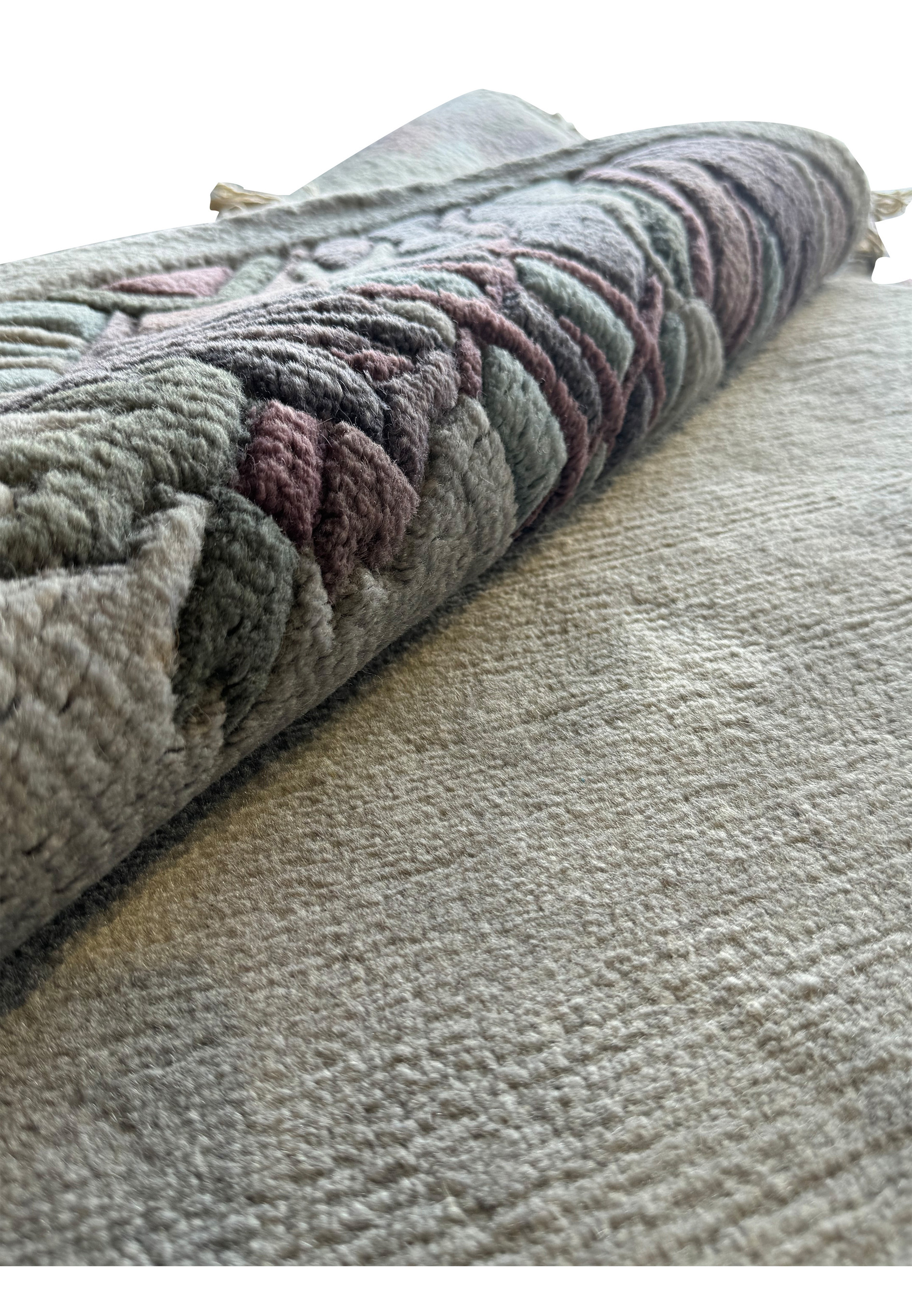 Nepal rug partially rolled to show the texture and thickness of the Tibetan sheep wool, along with the intricate border details.