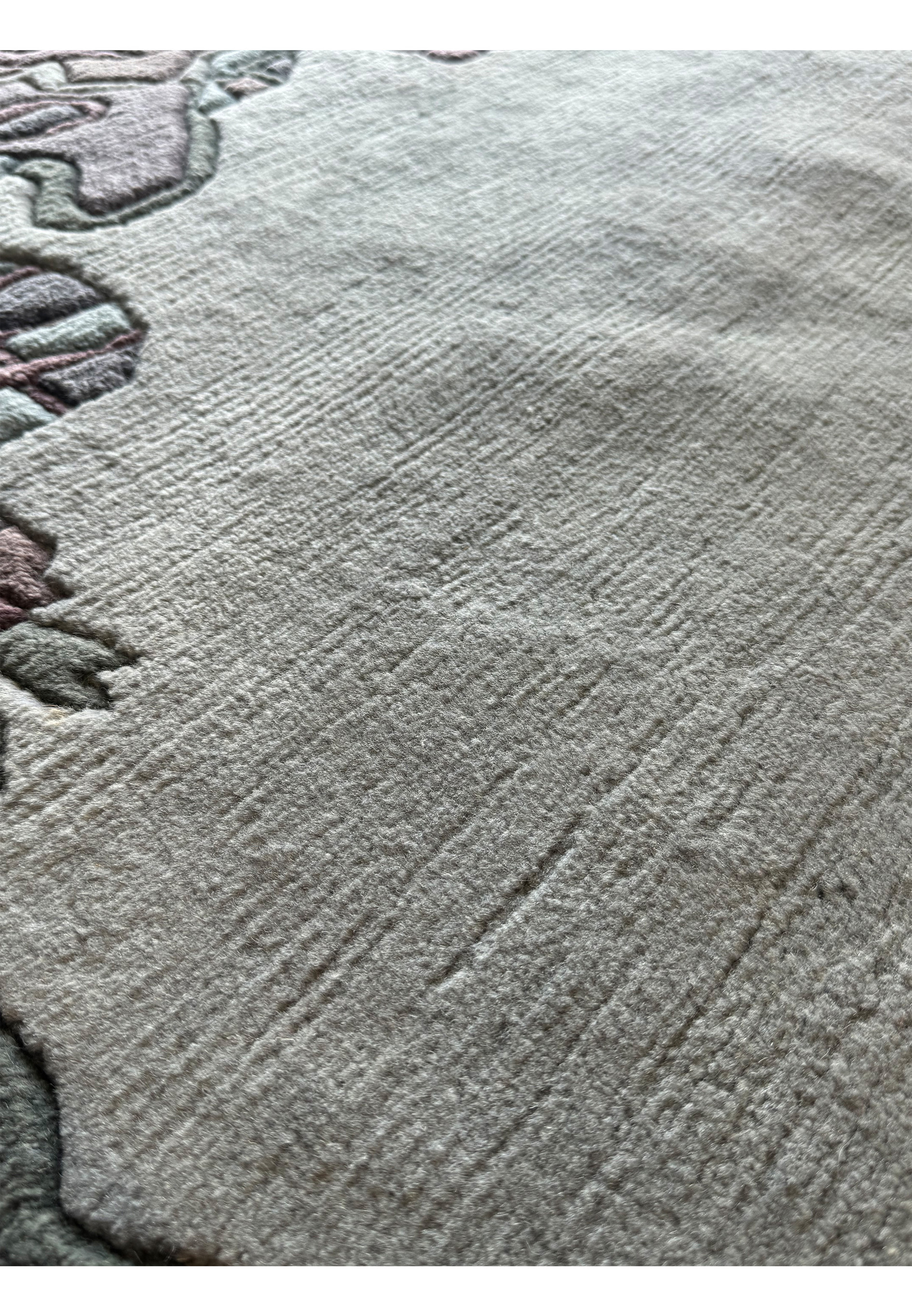 Close-up of the artistic border design on the Nepal rug, displaying a mix of abstract shapes in muted tones with a sculpted finish.
