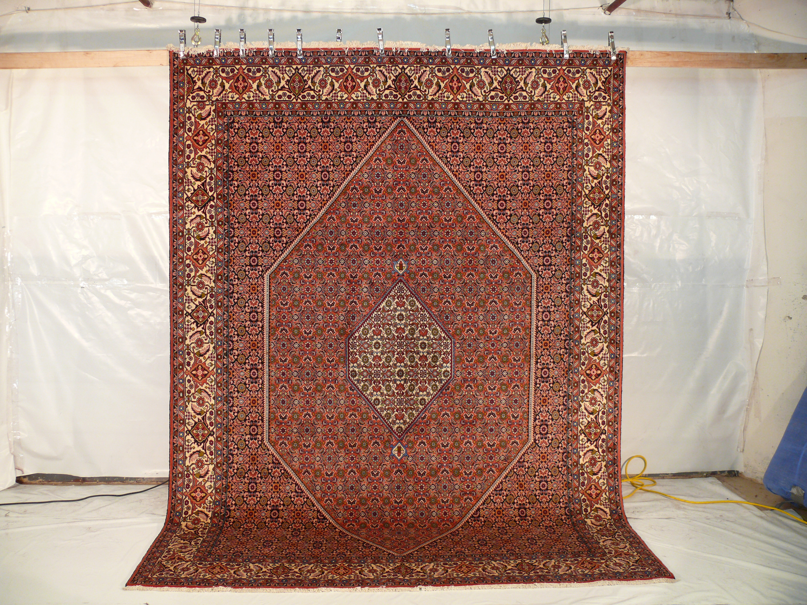 Persian Bijar rug 8x11 hung vertically to show scale, symmetry, and sharp detail under studio lighting