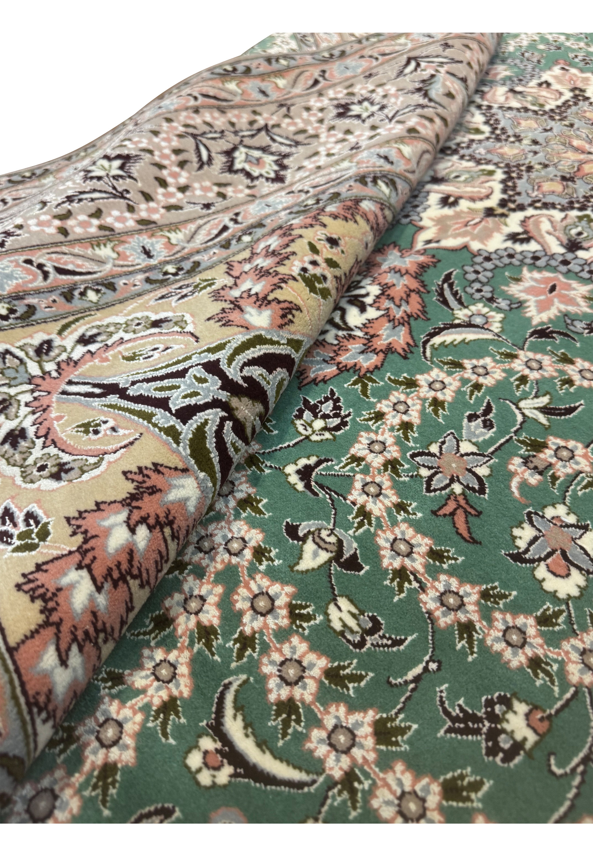 Rolled Persian Isfahan rug showing green field and silk floral motifs