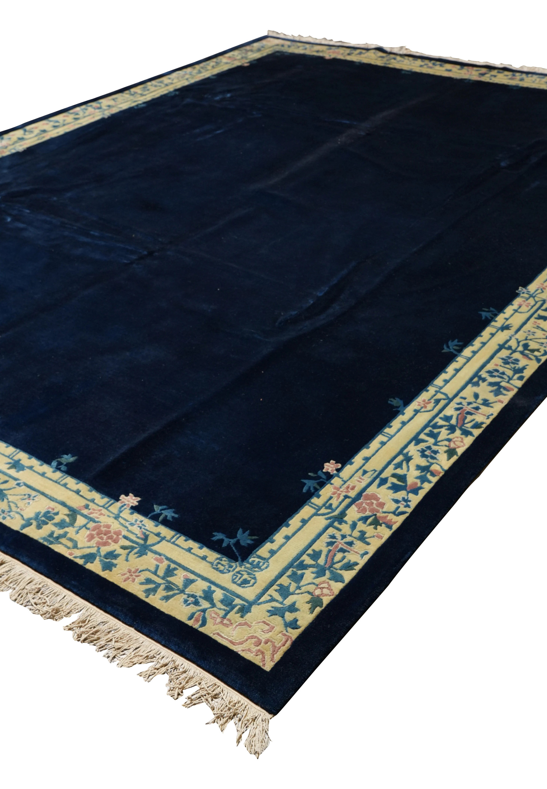 Angled view of 10x13’8 navy blue Beijing Art Deco rug with pastel floral border.