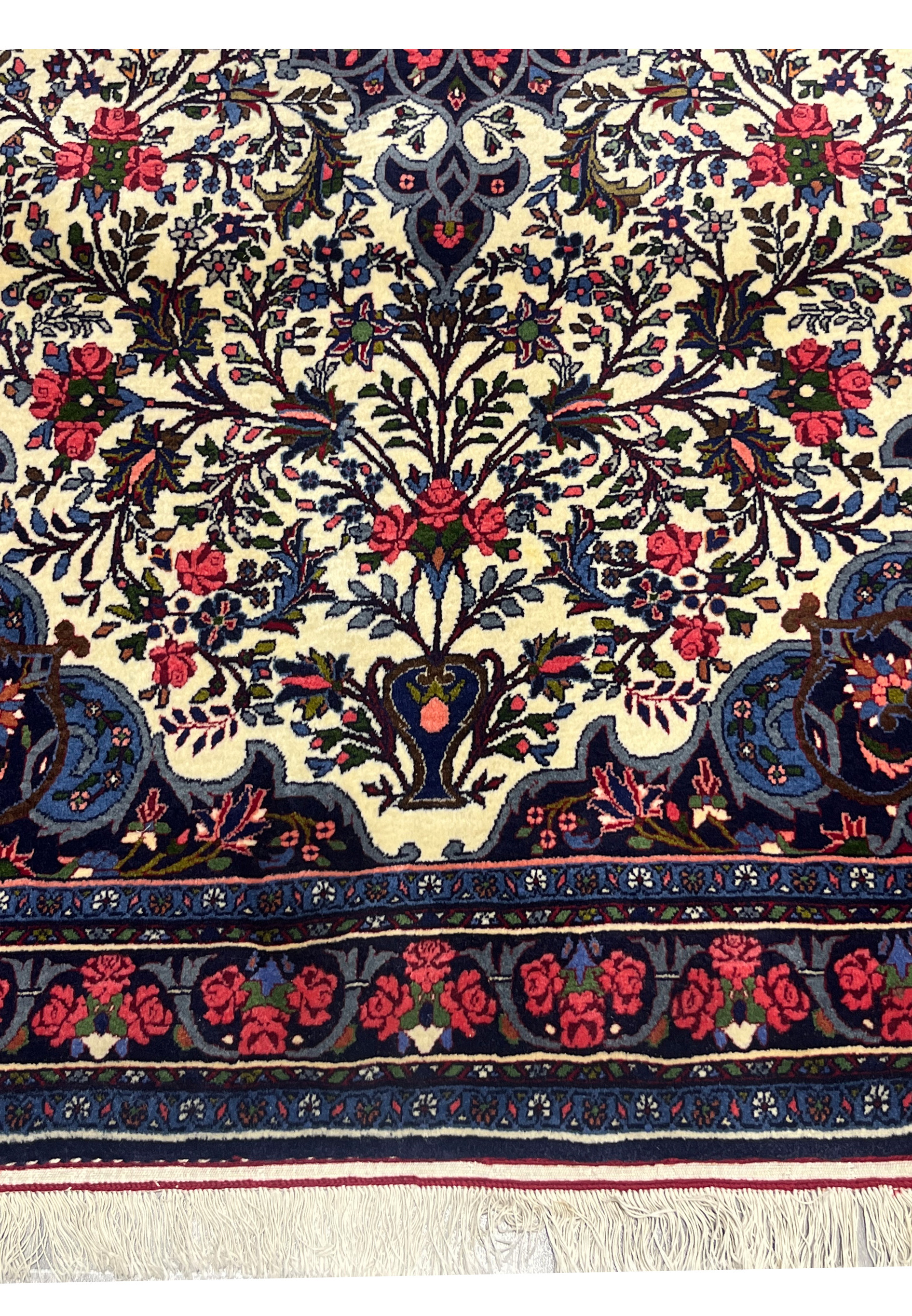 Lower edge of Persian Bijar Rug with floral border, fringes, and intricate roses on navy ground