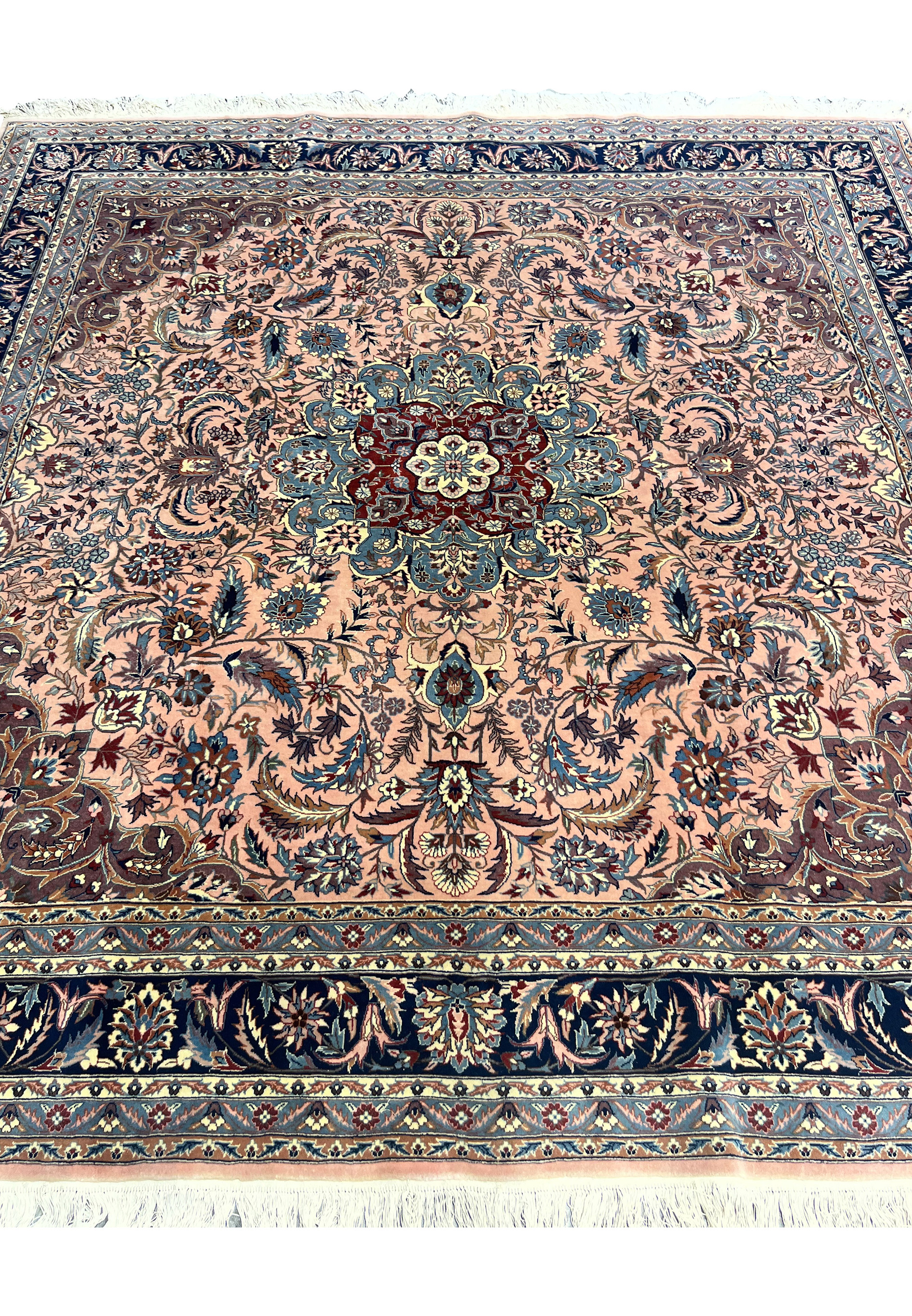 Detailed section of Persian Tabriz rug showing floral field and intricate vine work on salmon background