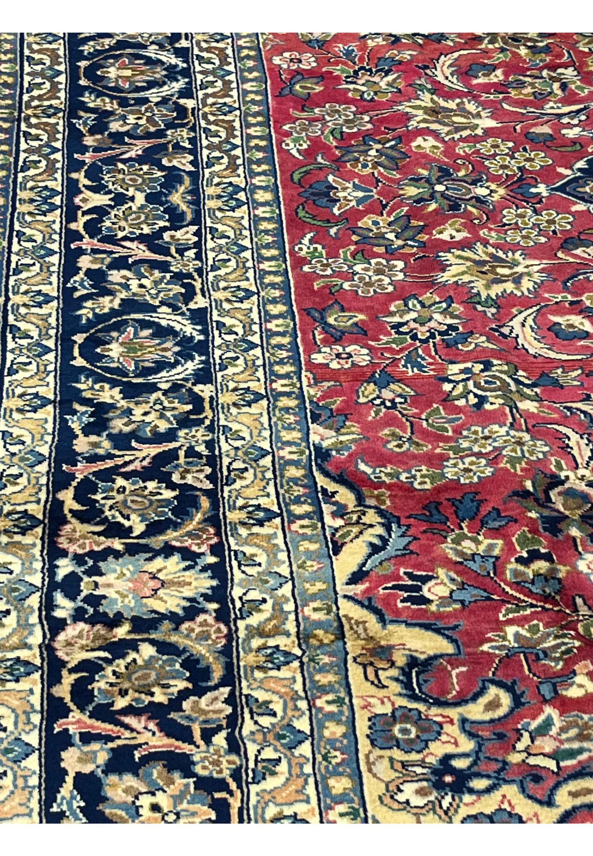 Close-up of color palette on the 8'7 x 12'7 Distressed Persian Isfahan Rug highlighting vivid red, navy, and ivory tones with floral detailing and aged patina texture.