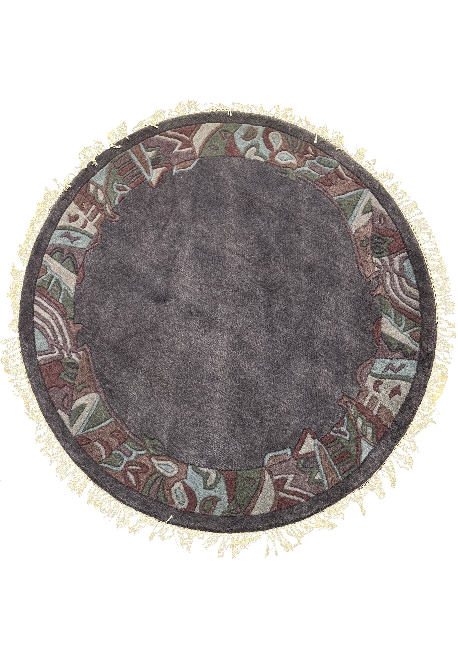 Full top-down view of the 5'3 x 5'3 Round Modern Nepal Rug showcasing its charcoal-gray wool field and hand-carved abstract border in olive, burgundy, and blue tones with light fringes.