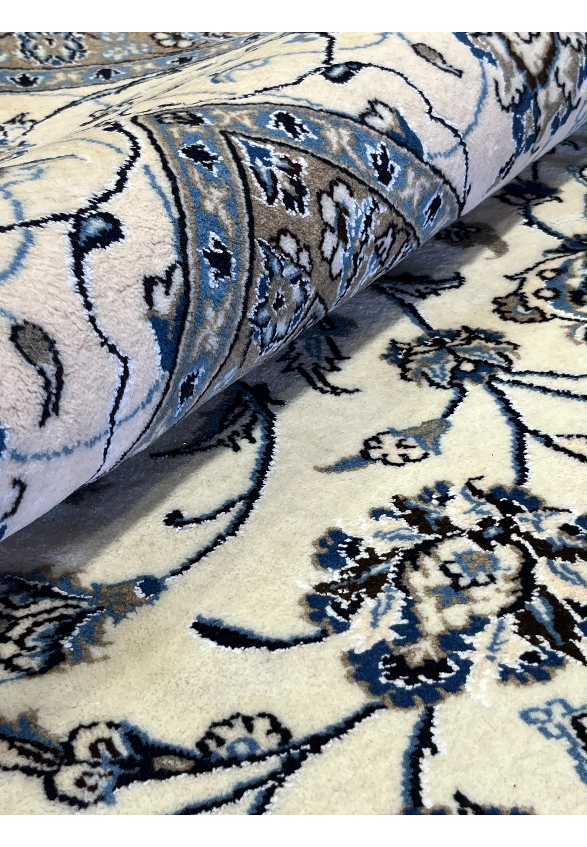 Rolled 10x13 Persian Nain 9LA Rug highlighting ivory and blue field with silk shimmer and fine floral detailing.