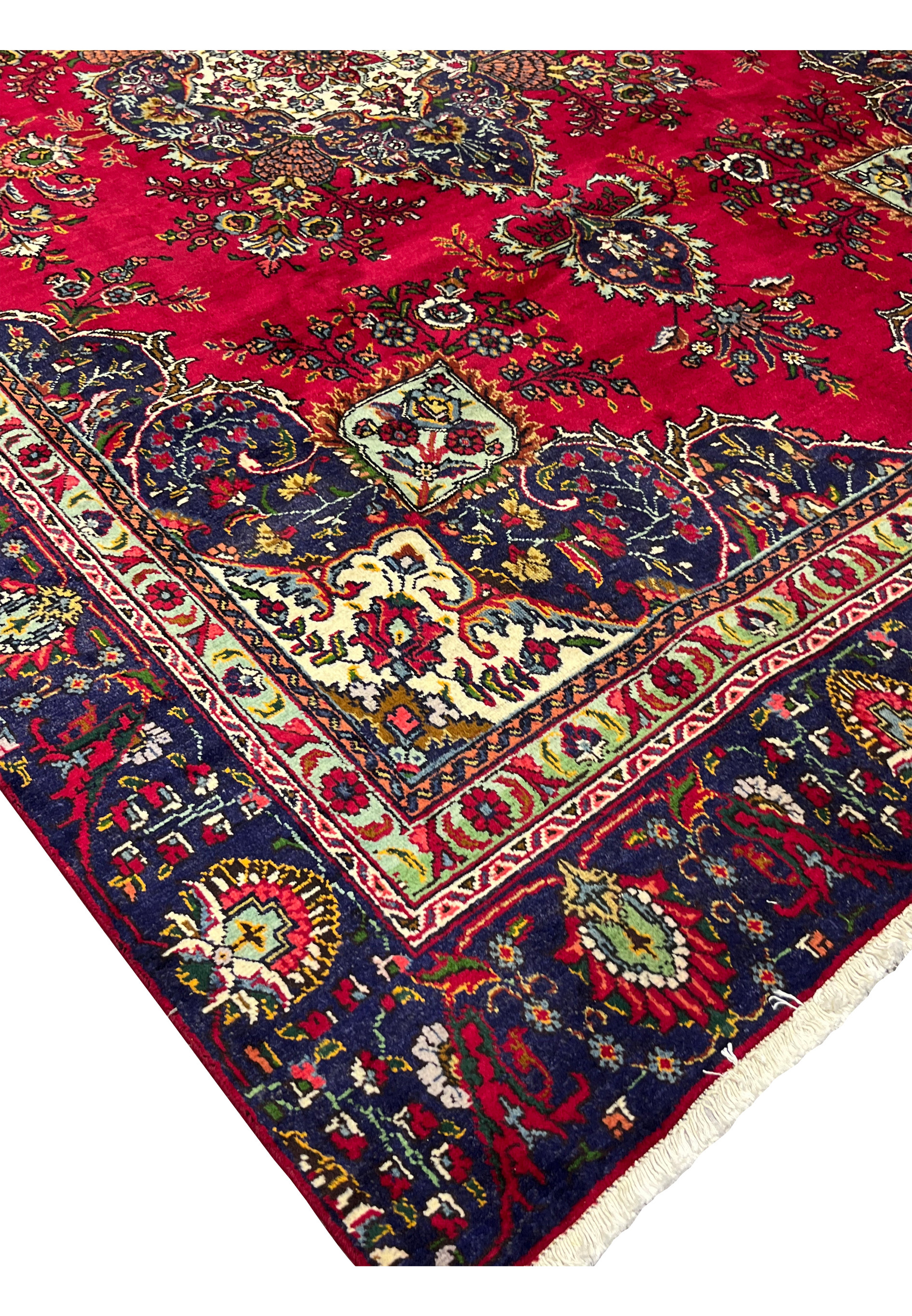 Corner edge of Persian Tabriz wool rug with intricate navy border and ivory floral accents