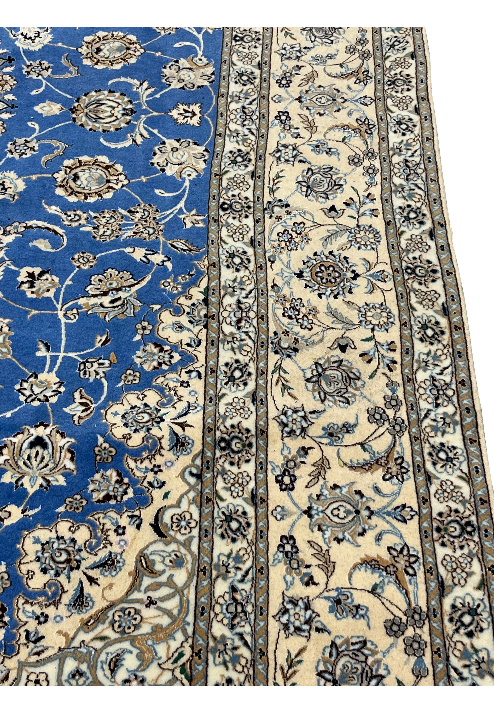 Side edge of hand-knotted Persian Nain rug showing wool and silk detail and royal blue field