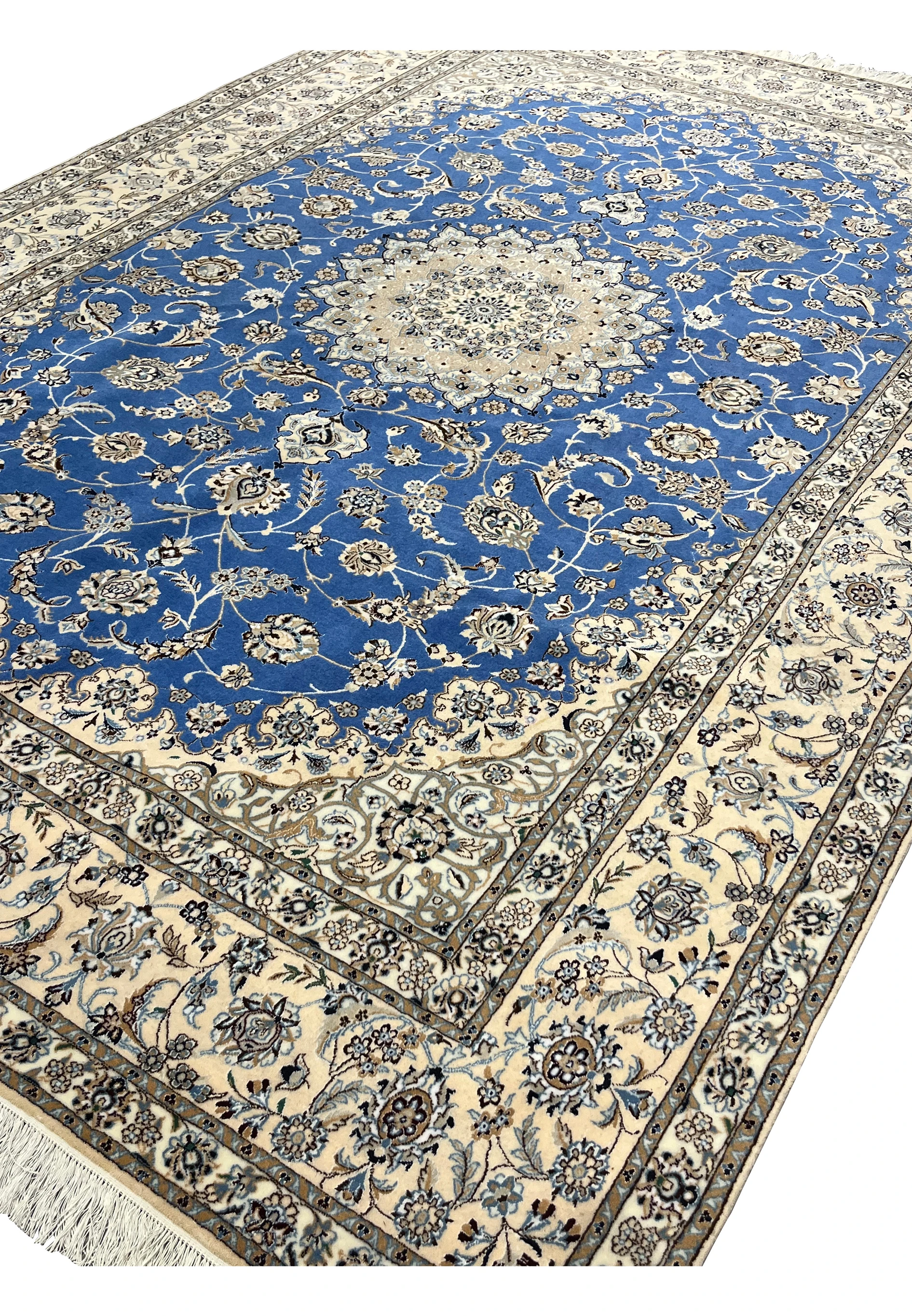 Angled view of Persian Nain 6 LA wool and silk rug showing royal blue field with ivory and beige floral motifs