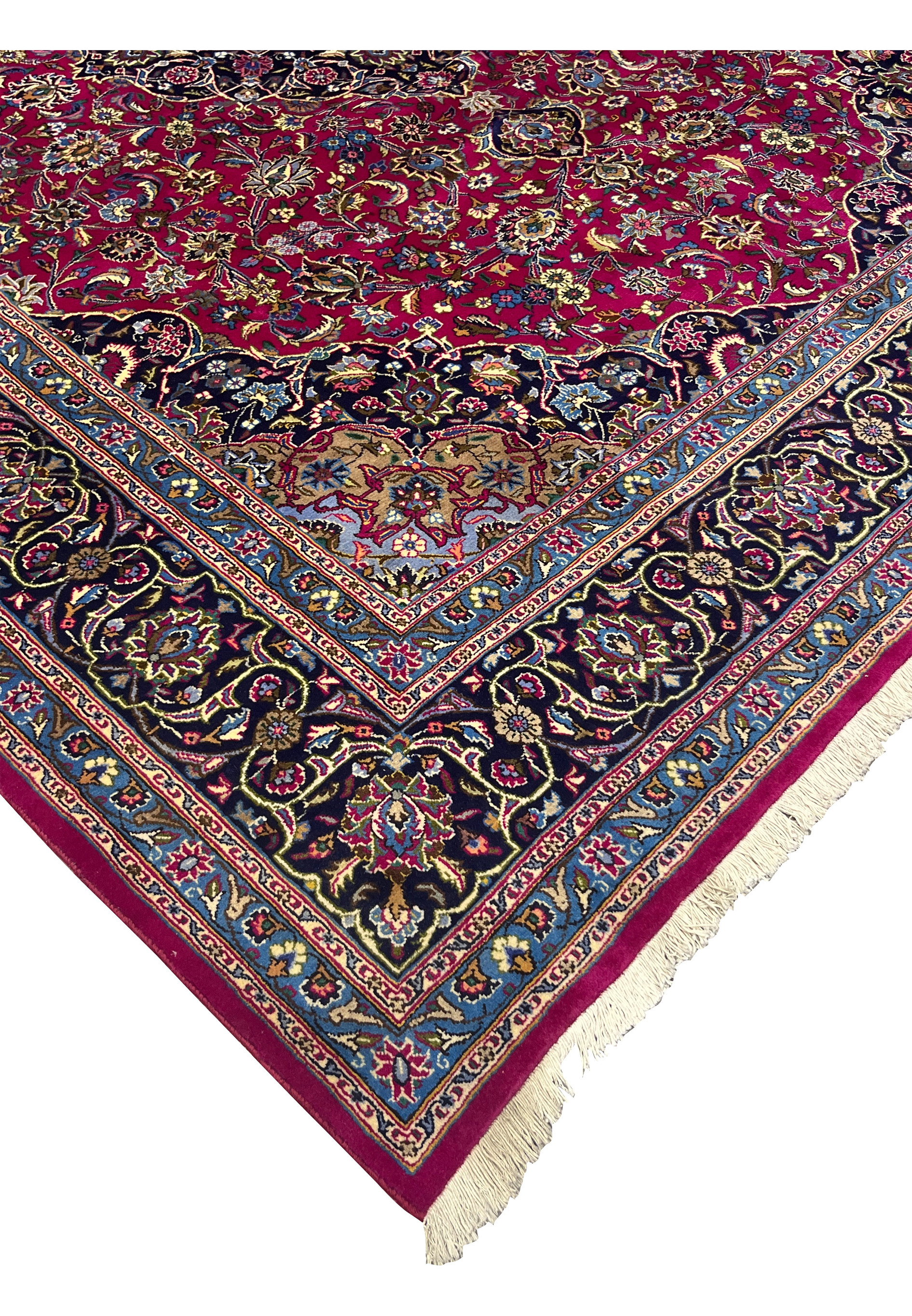 Edge view of Mashad rug showing fine weave, ruby border, and ivory fringe.