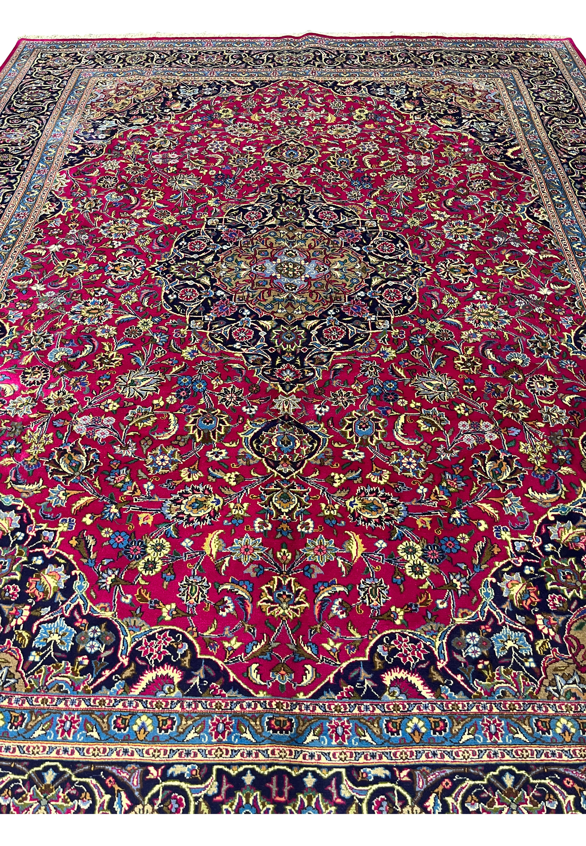 Top full view of Persian Mashad red wool rug showing floral medallion and navy borders.
