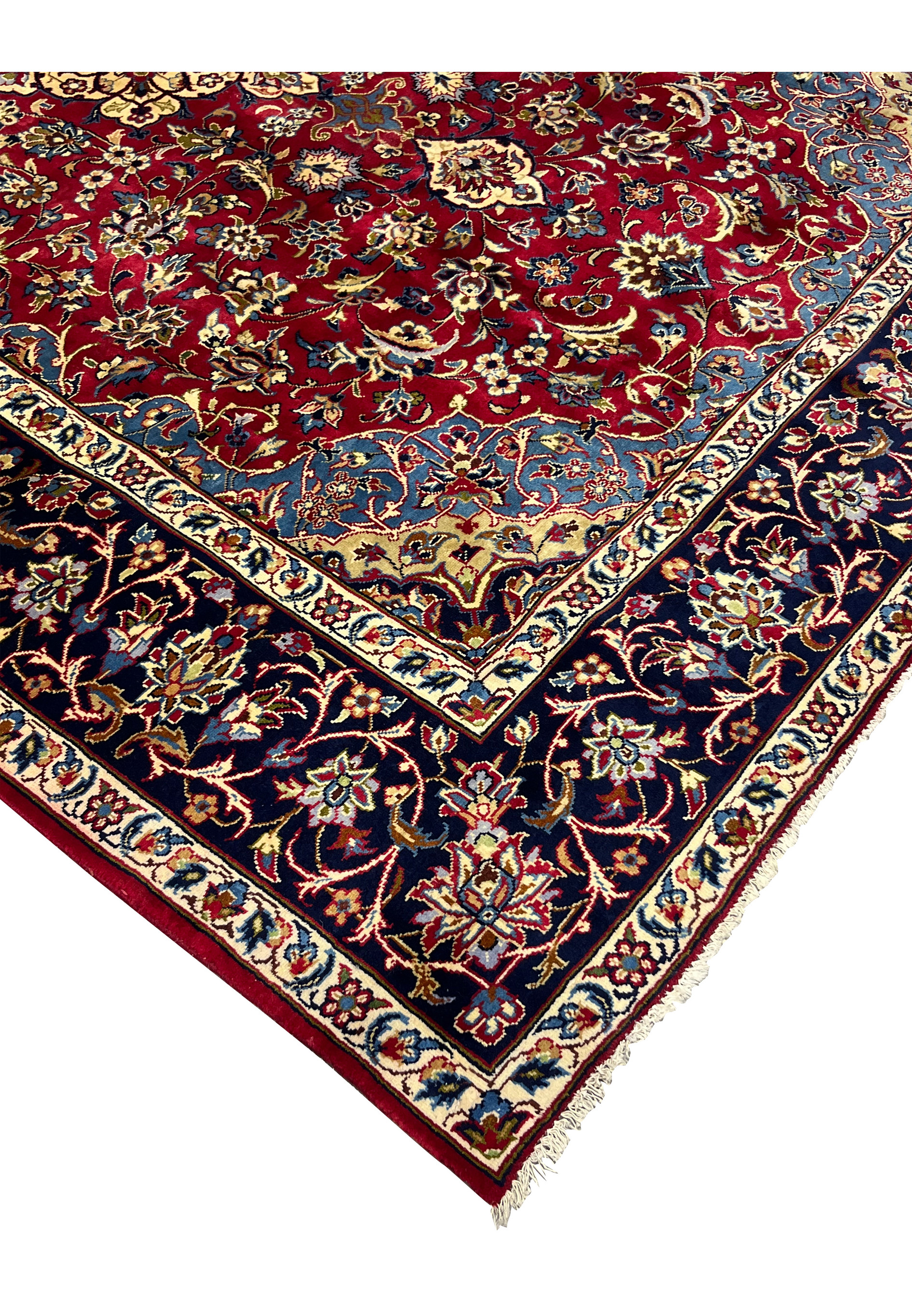 Edge of 8'5 x 11'8 Persian Isfahan rug showing fringe, navy border, and wool floral detailing.