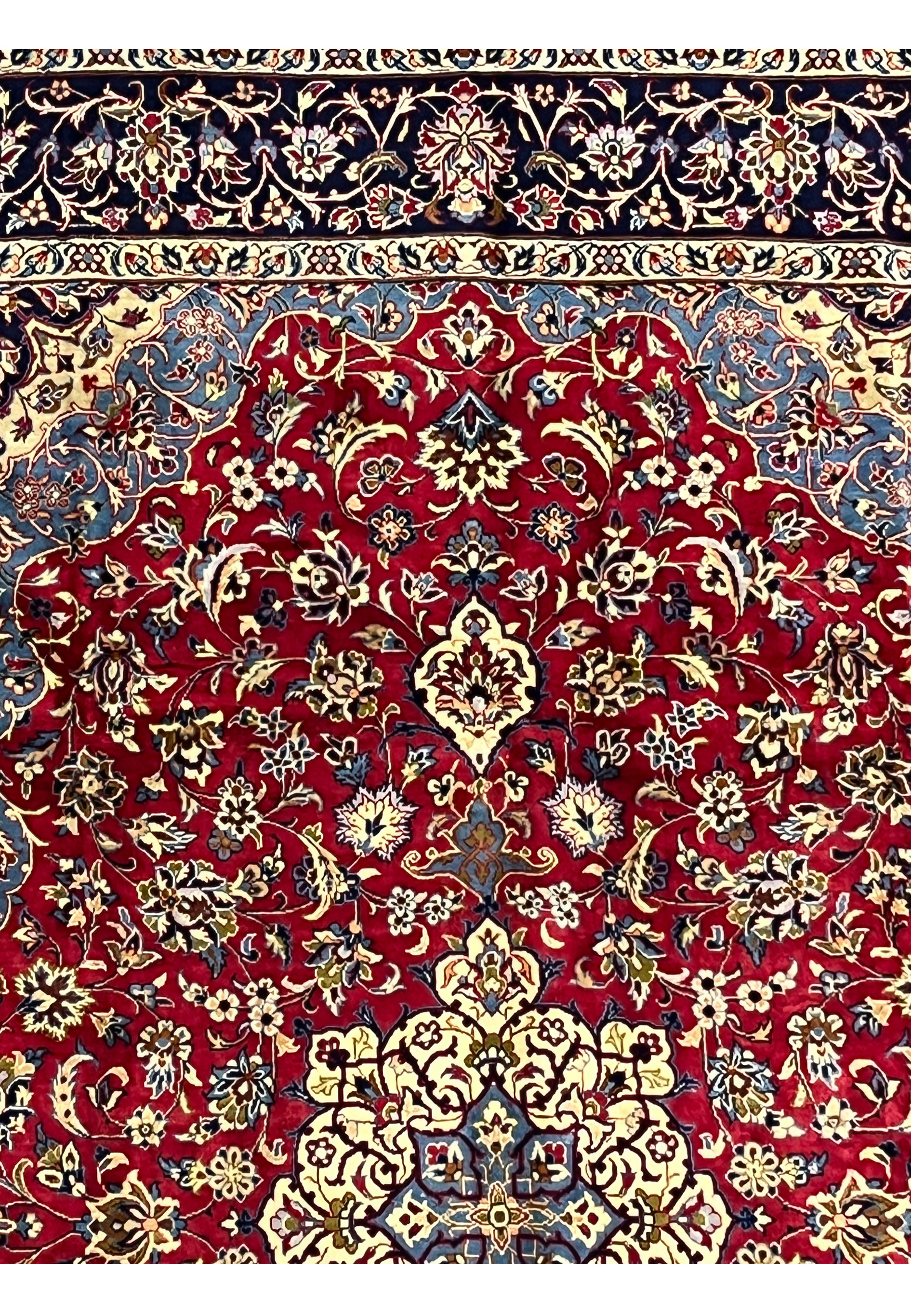 Upper border of 8'5 x 11'8 Persian Isfahan rug with red floral field and light blue corner spandrels.