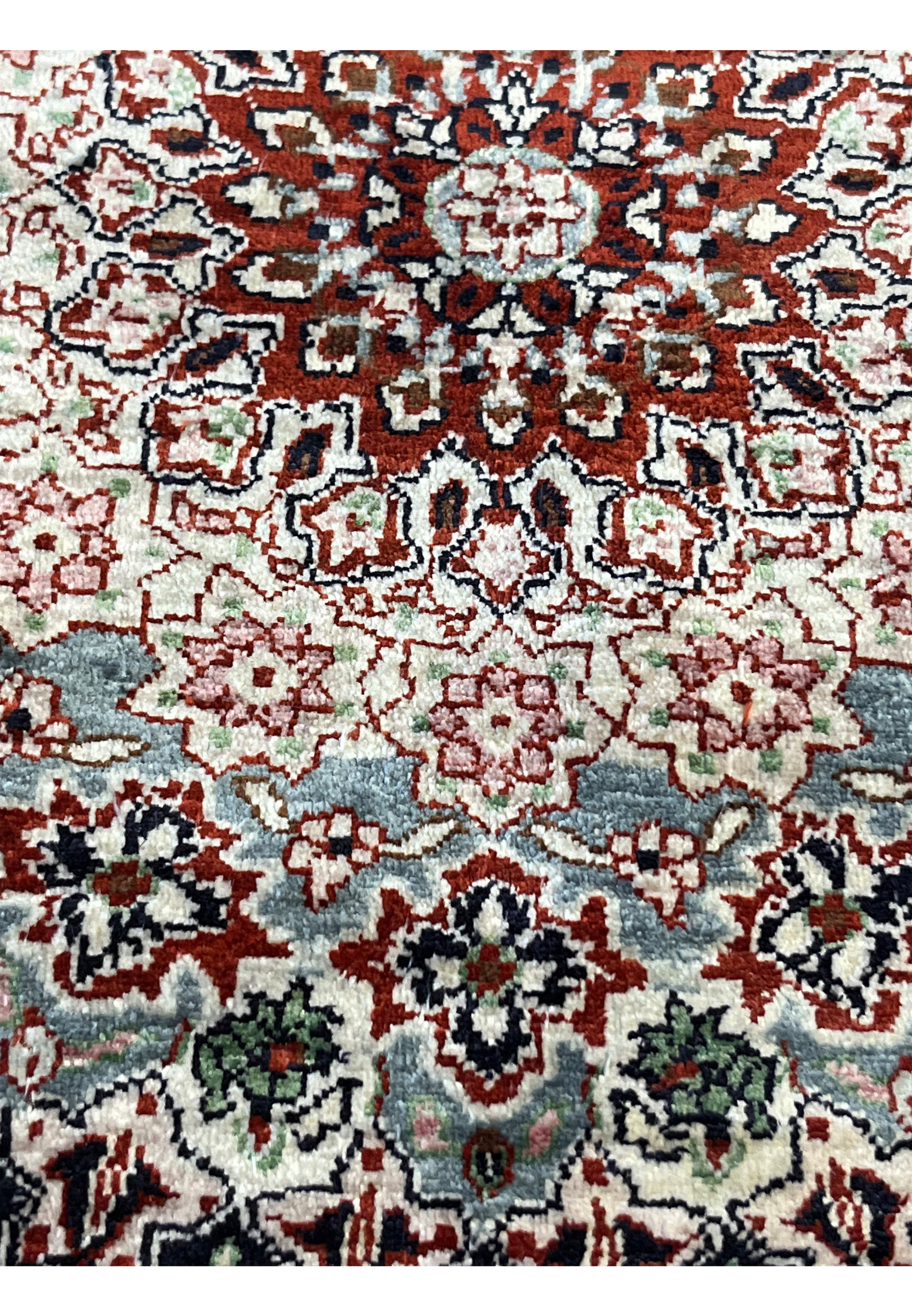 Detailed color close-up of Qum silk rug showing mint green field, burgundy accents, soft pink florals, and navy outlines.