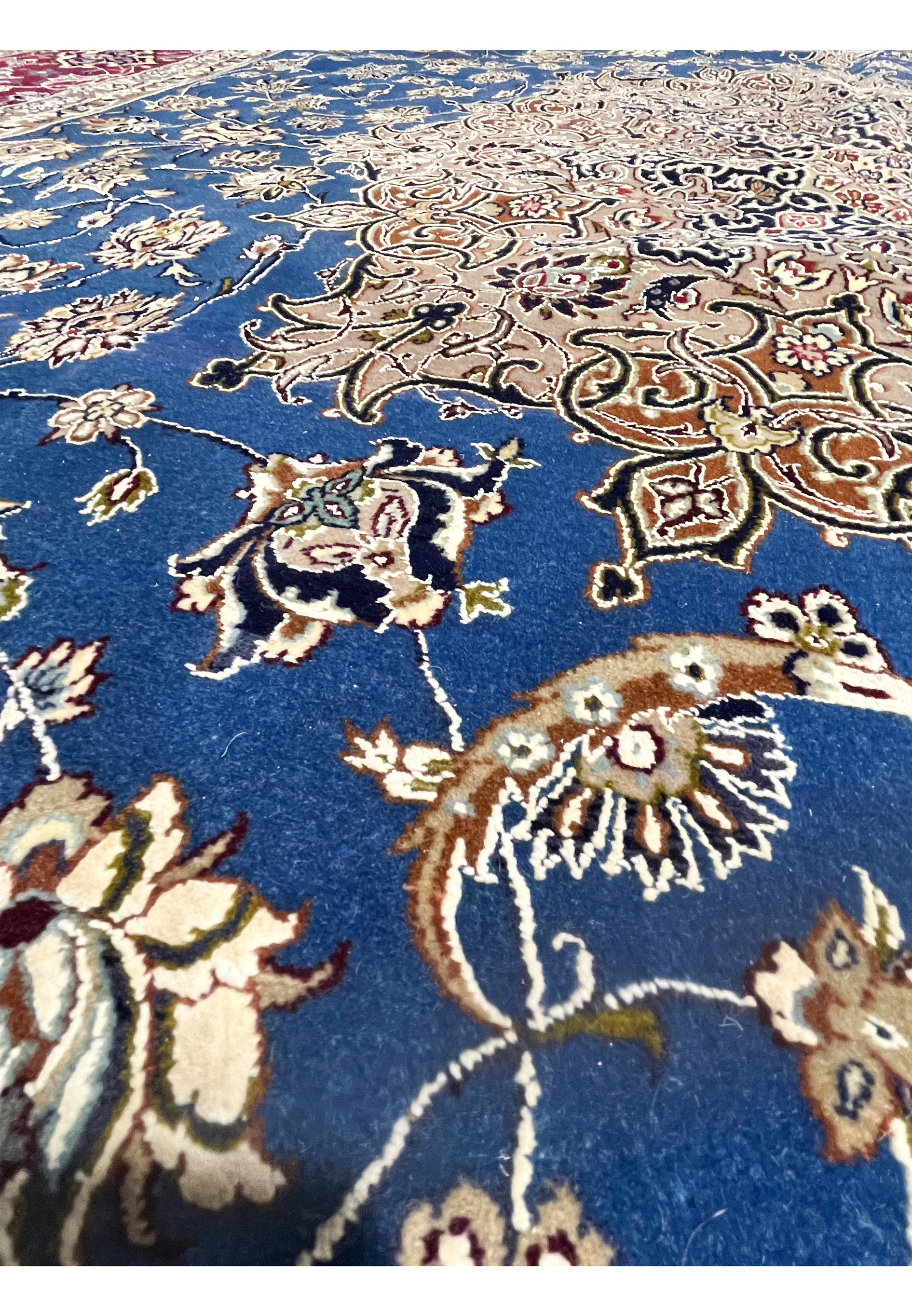 Color close-up capturing wool and silk texture with blue floral field, ivory accents, and fine detailing in the Persian Isfahan weave.
