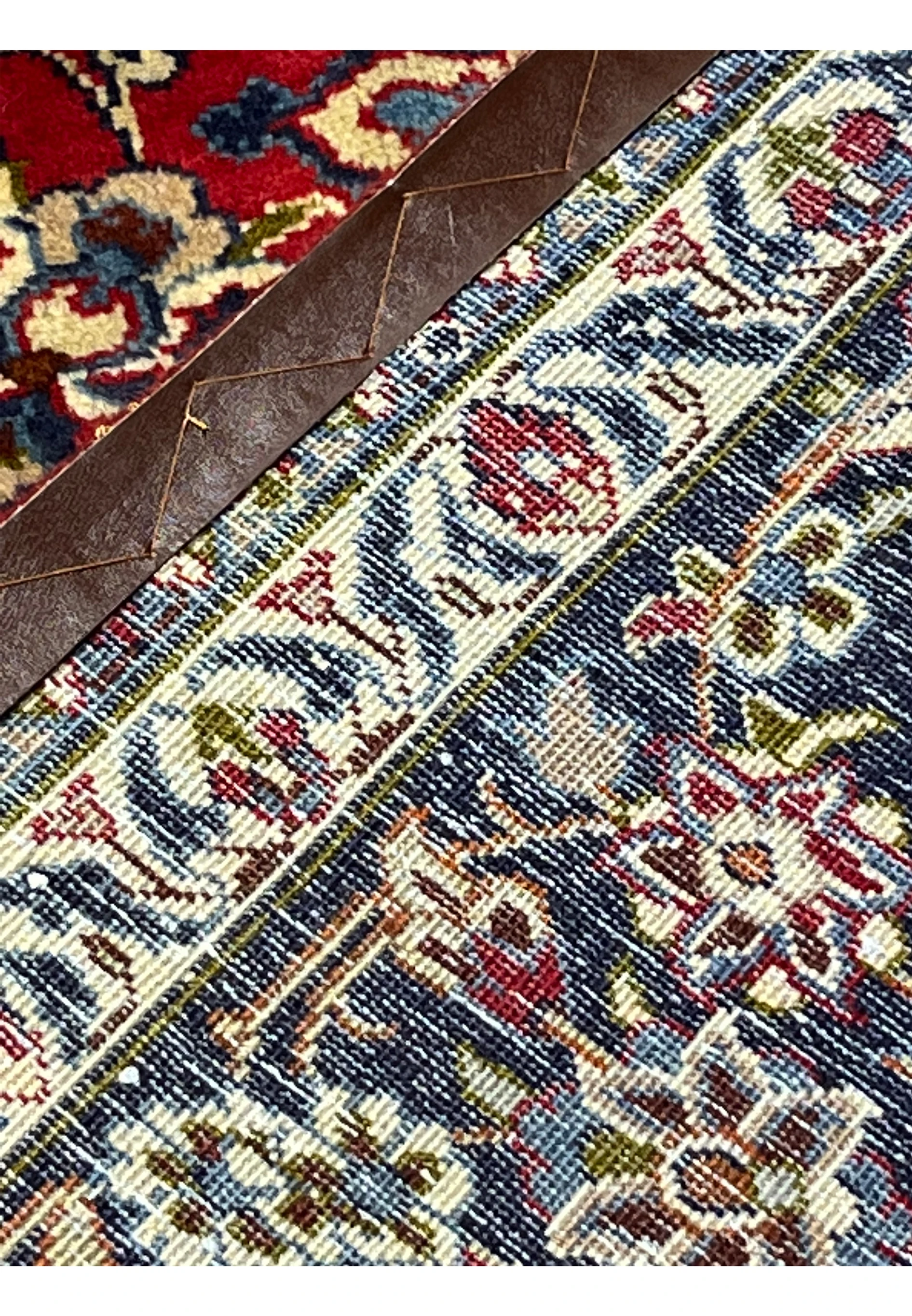 Backside close-up of 9'10 x 13'1 Persian Isfahan rug showing leather edging, fine knot structure, and detailed floral border pattern