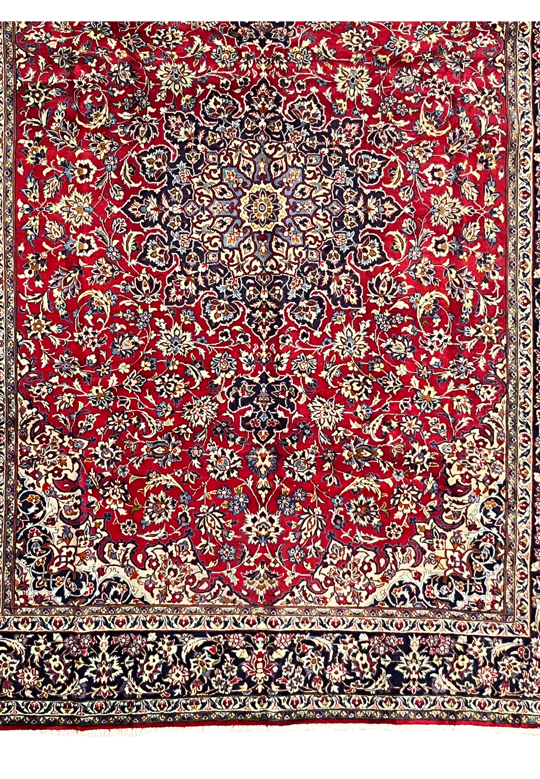Lower section of Persian Isfahan rug displaying ruby red floral field and transition to navy border