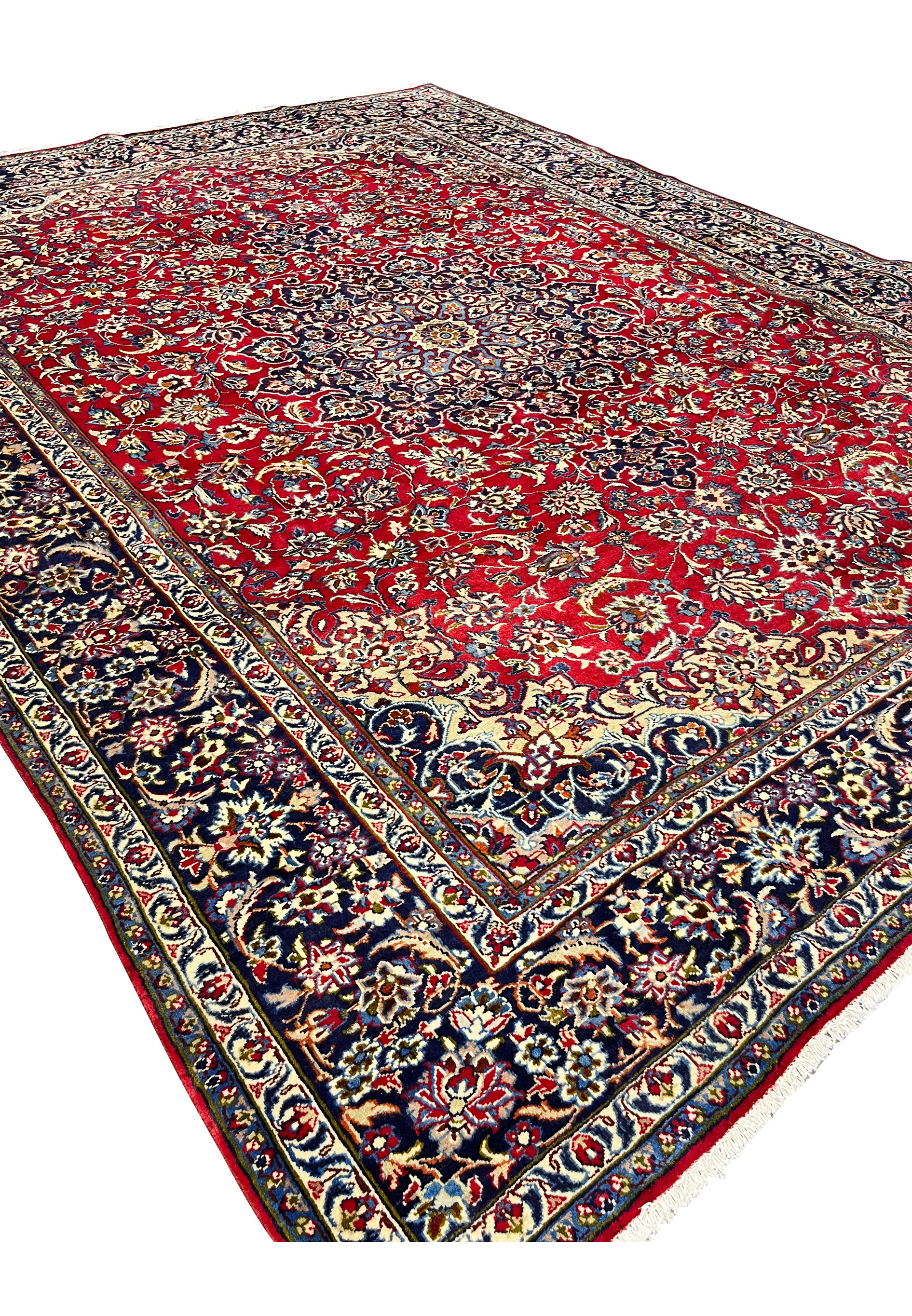 Angled view of 9'10 x 13'1 Persian Isfahan rug displaying medallion, floral designs, ruby field, and navy borders