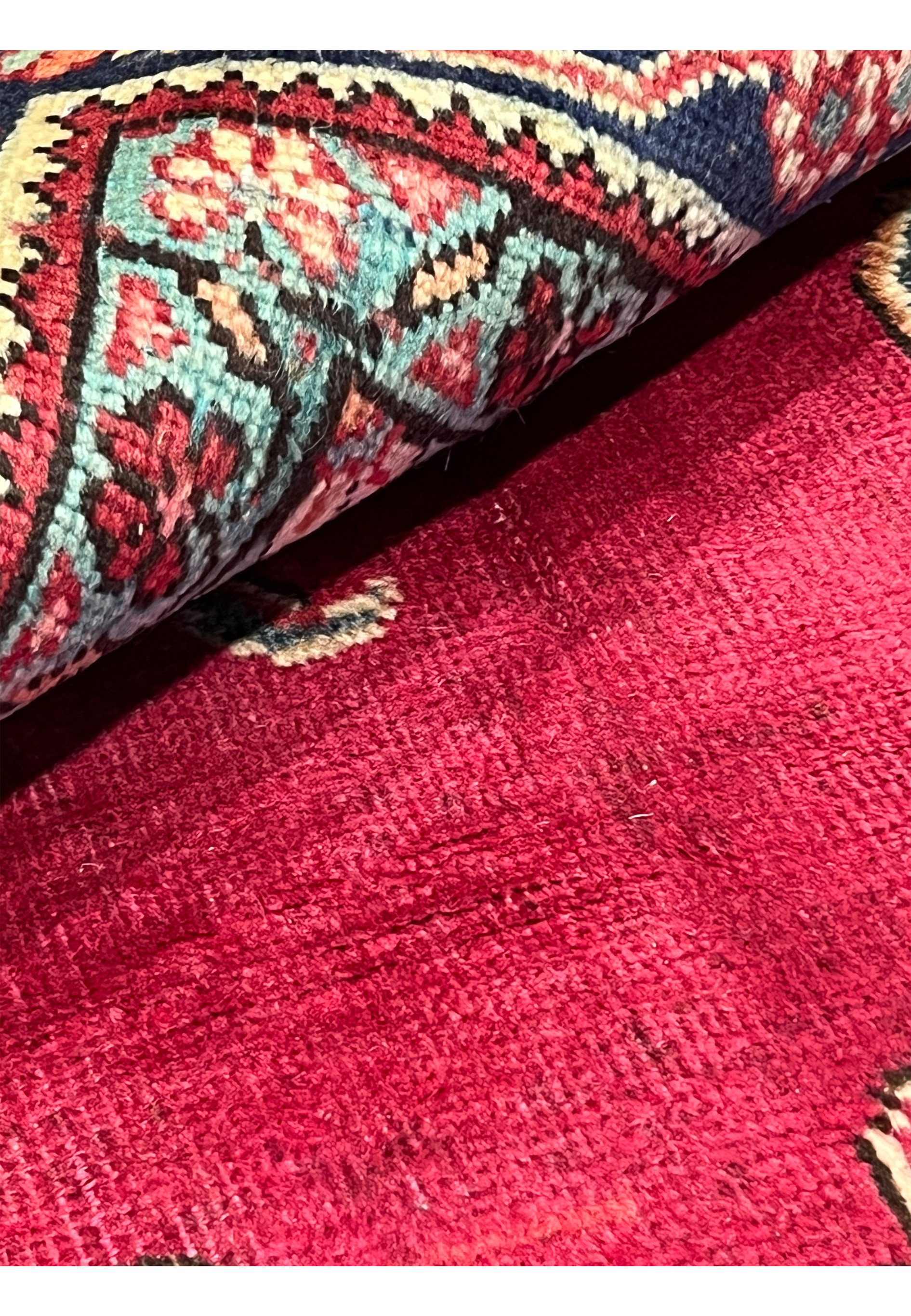 Detailed closeup of low-pile patina on Persian Tabriz rug with faded red wool and visible wear consistent with vintage character.