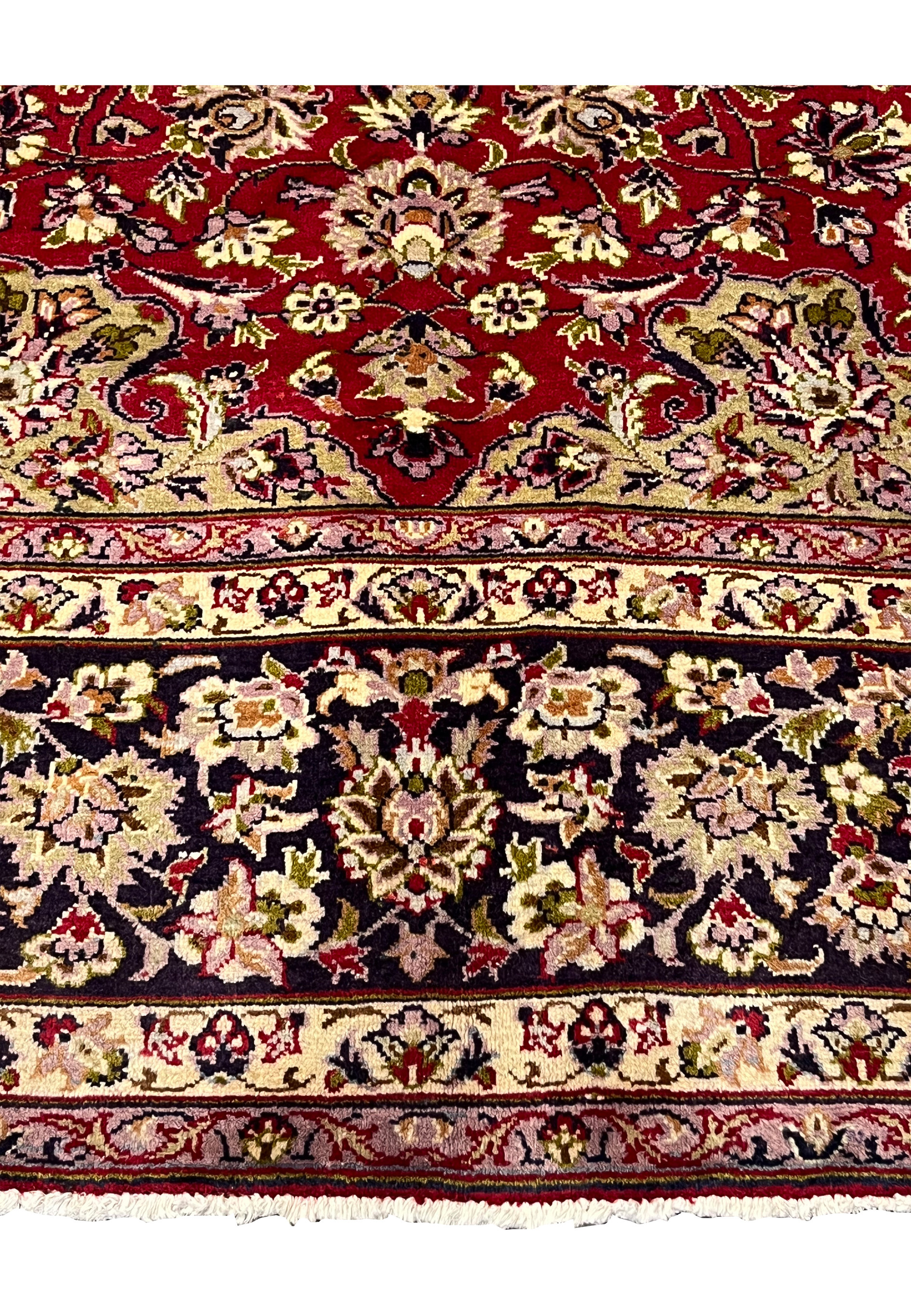Border closeup of red Persian Isfahan rug showing navy floral motifs and guard stripes