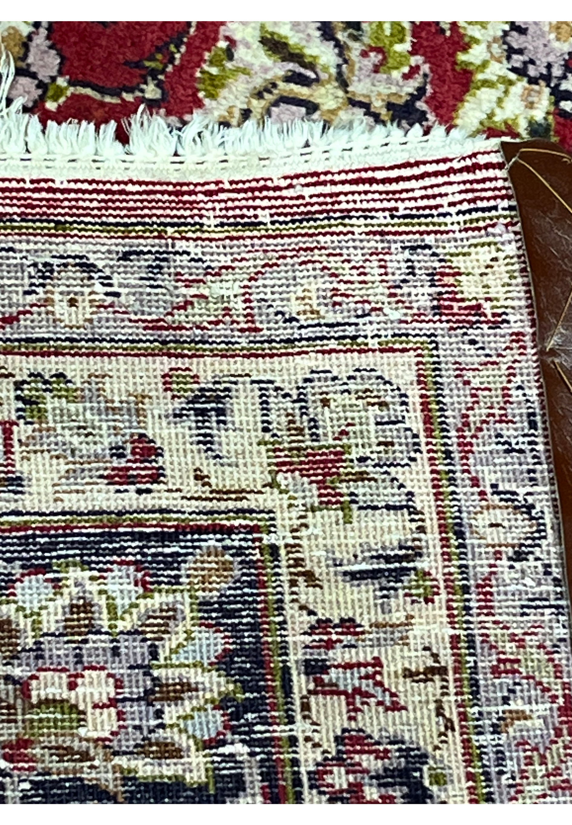 Detailed view of the Persian Isfahan rug’s back with visible warp and weft lines, multicolor floral motifs, and secure leather edge reinforcement.