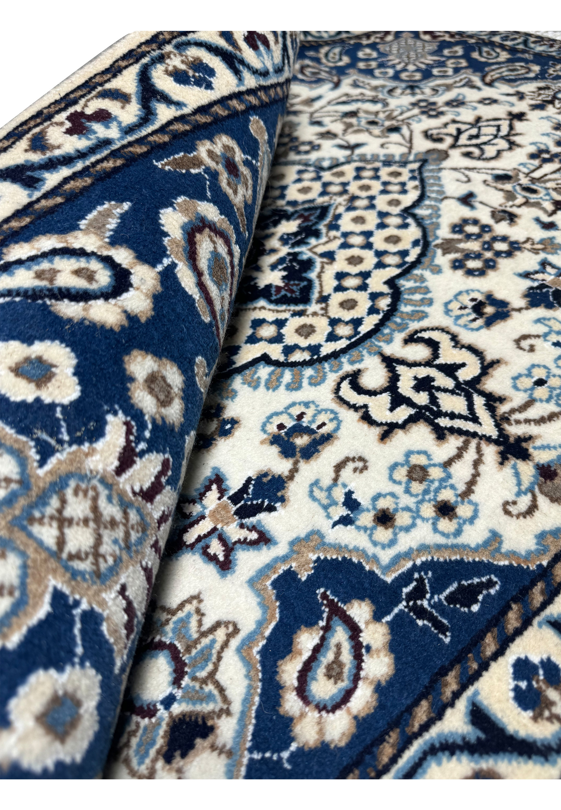 Rolled view of Persian Nain rug displaying thick wool pile, crisp navy and ivory color contrast, and tightly woven cotton foundation