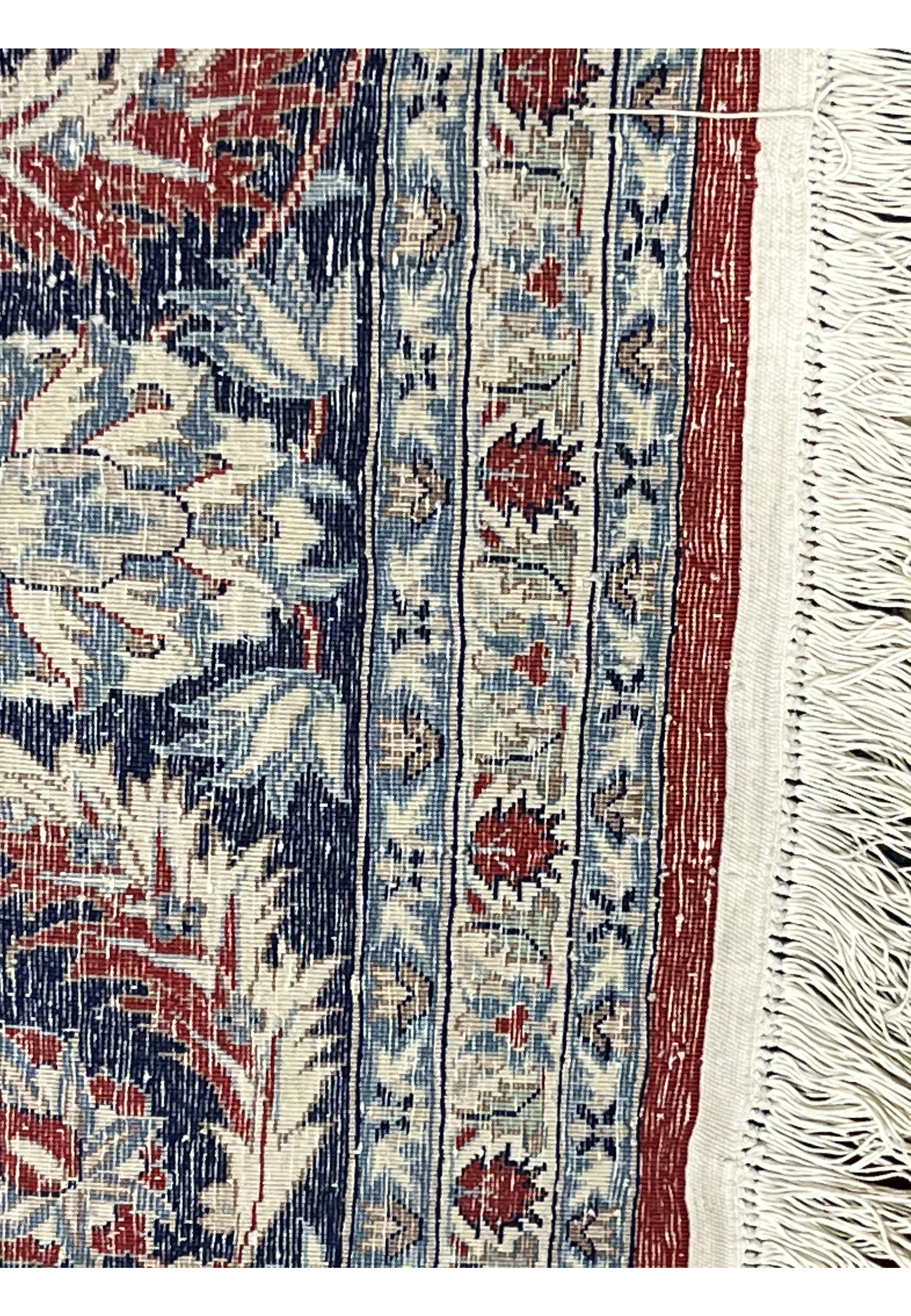 Backside of Persian Isfahan rug showing tight hand-knot structure, aligned wool foundation, detailed border pattern, and ivory fringe.