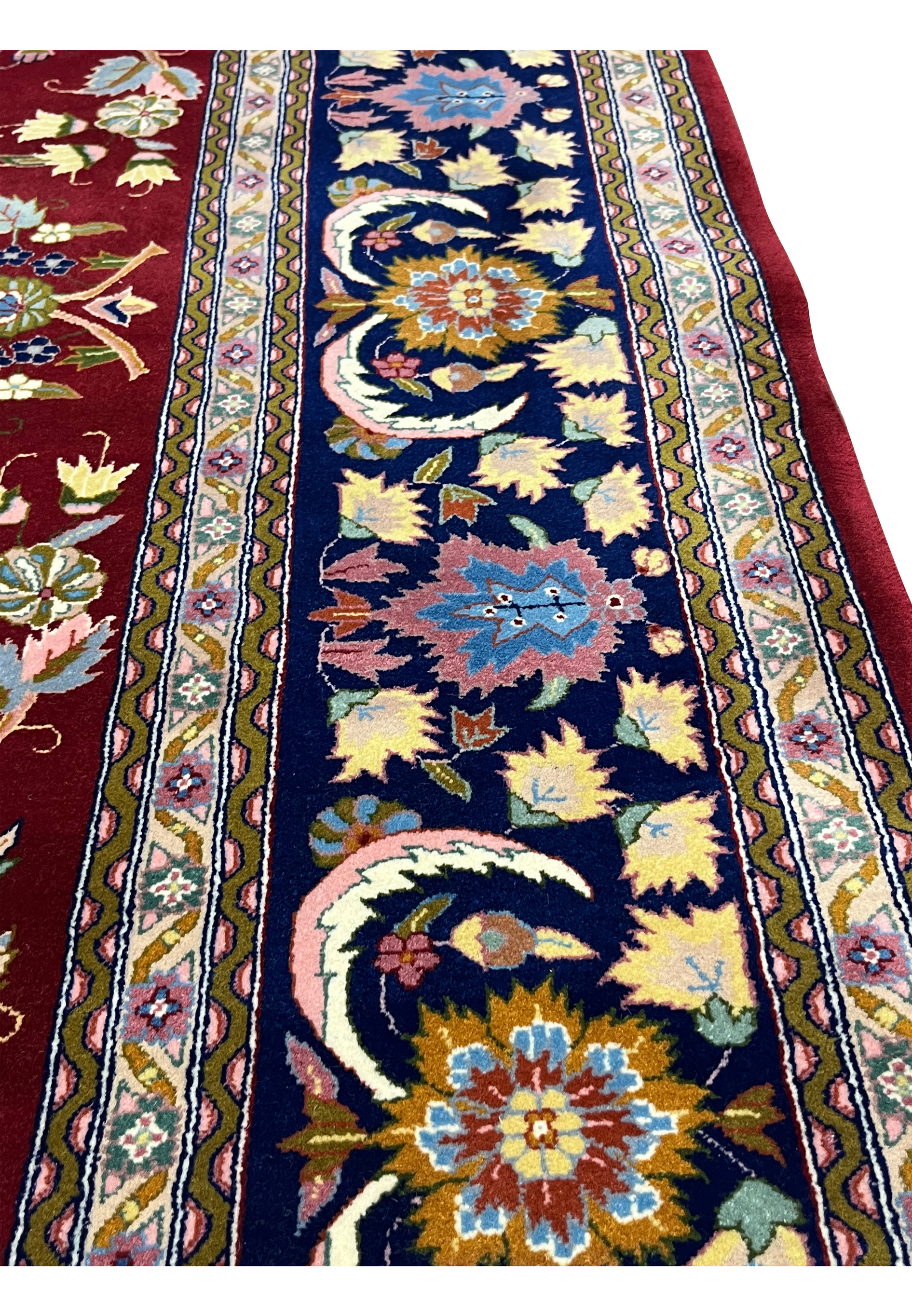 Close-up of navy border on Persian Isfahan rug with floral rosettes, palmettes, and vine motifs