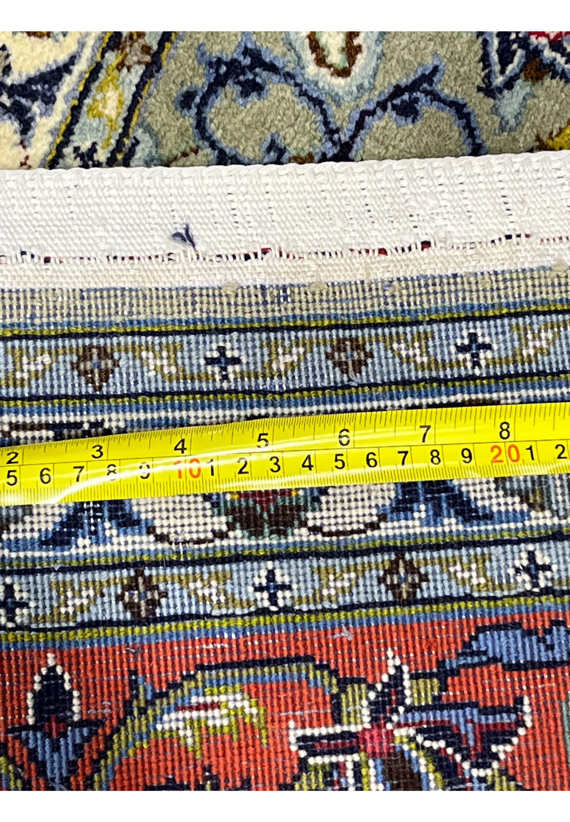 Backside of green Persian Kashan rug with ruler showing knot density and scale