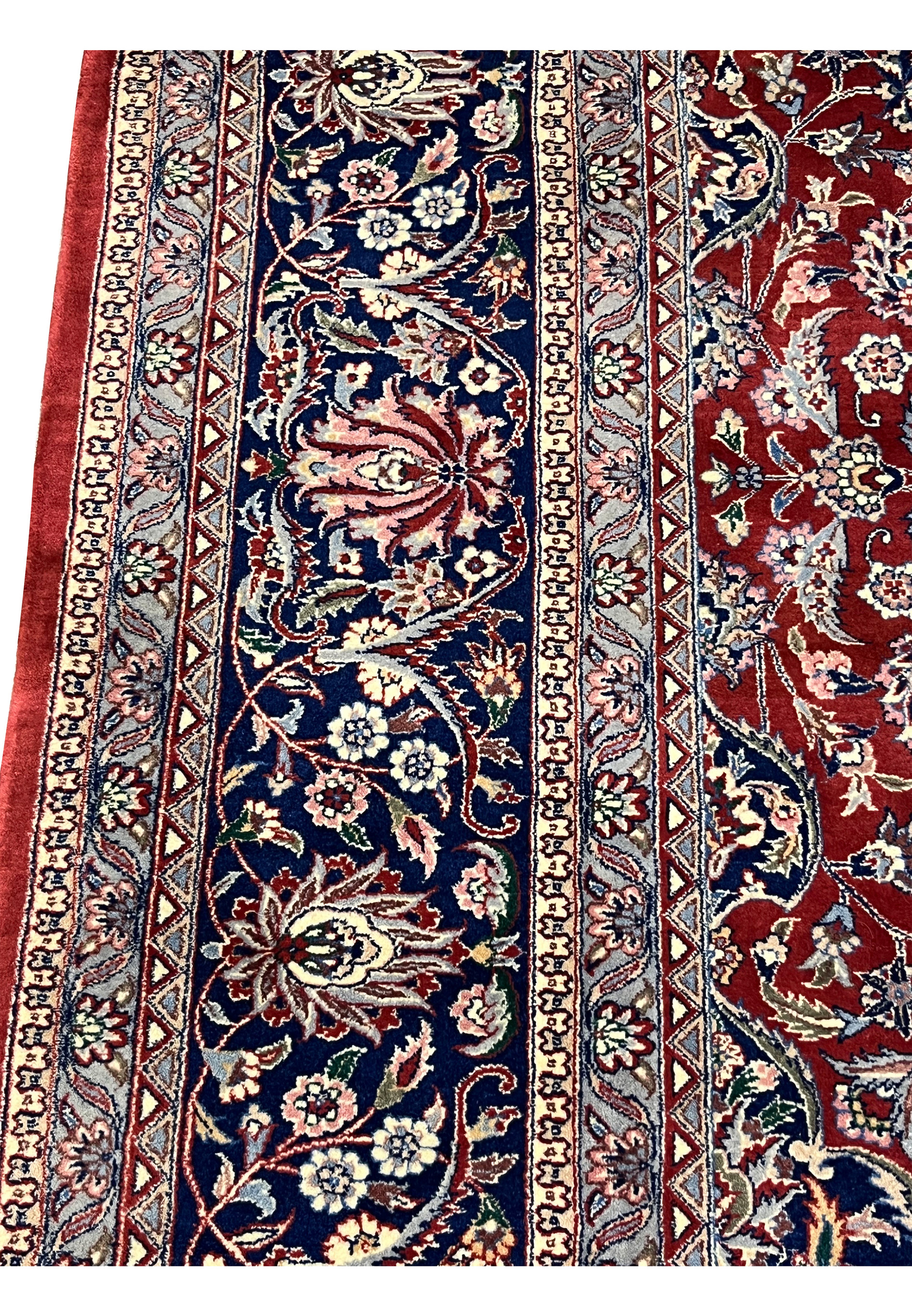Side border close-up showing floral motifs on navy Kashan rug border