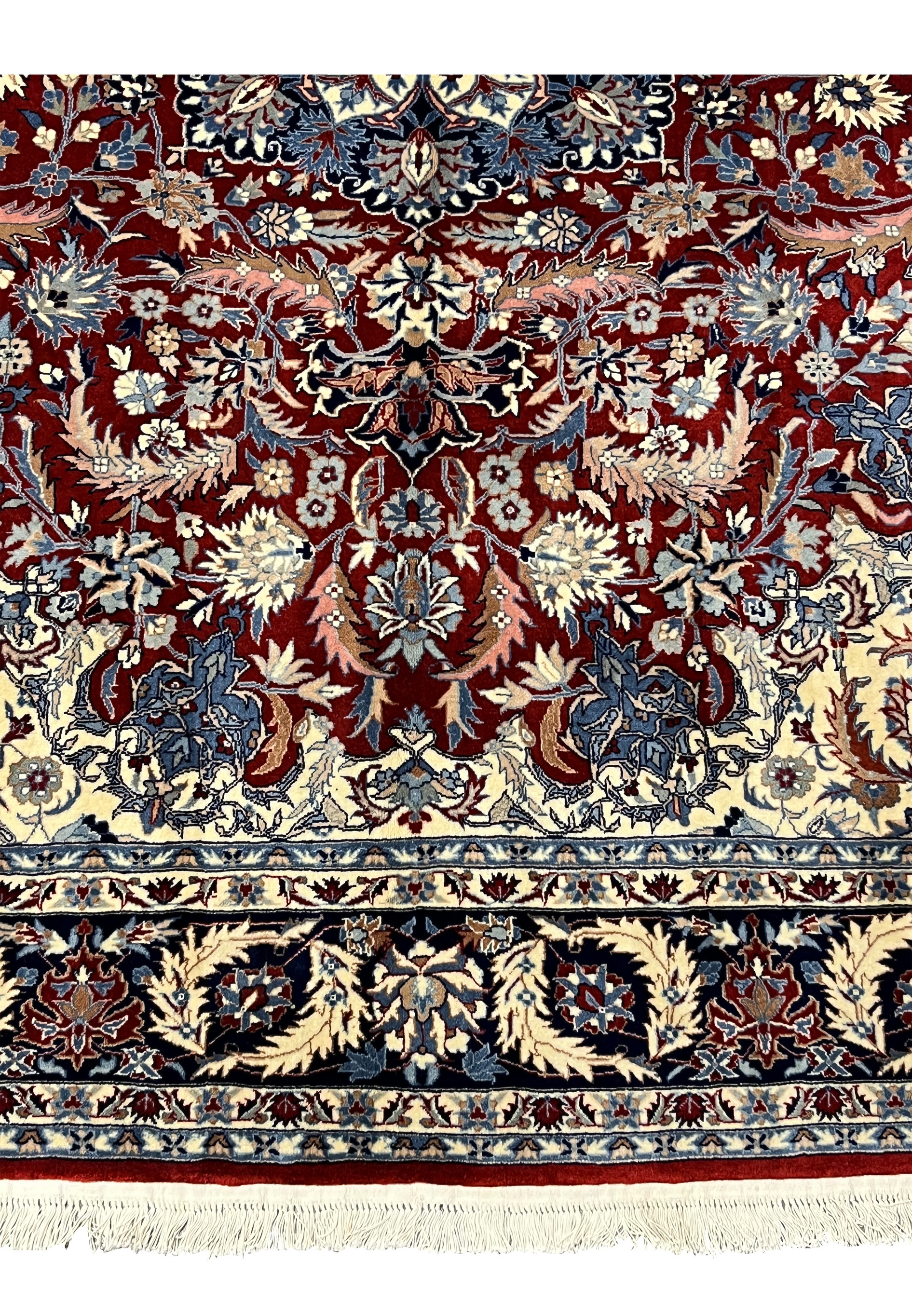 Lower end detail of Persian Tabriz rug showing navy border, ivory guard borders, burgundy field, and fringe finish