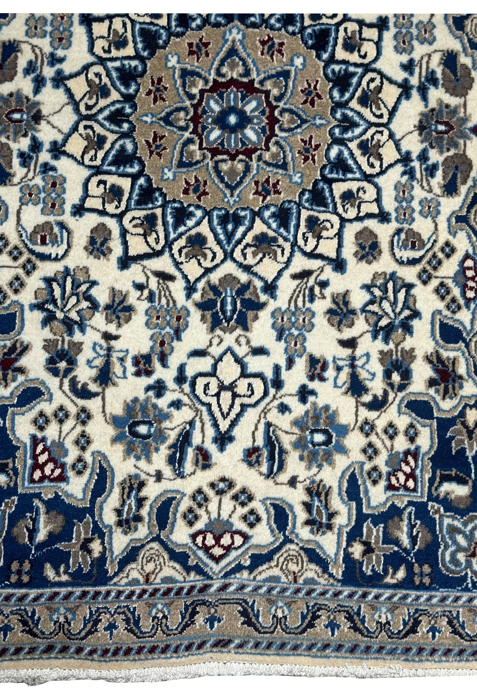 Lower border detail of Persian Nain rug with blue and beige floral patterns