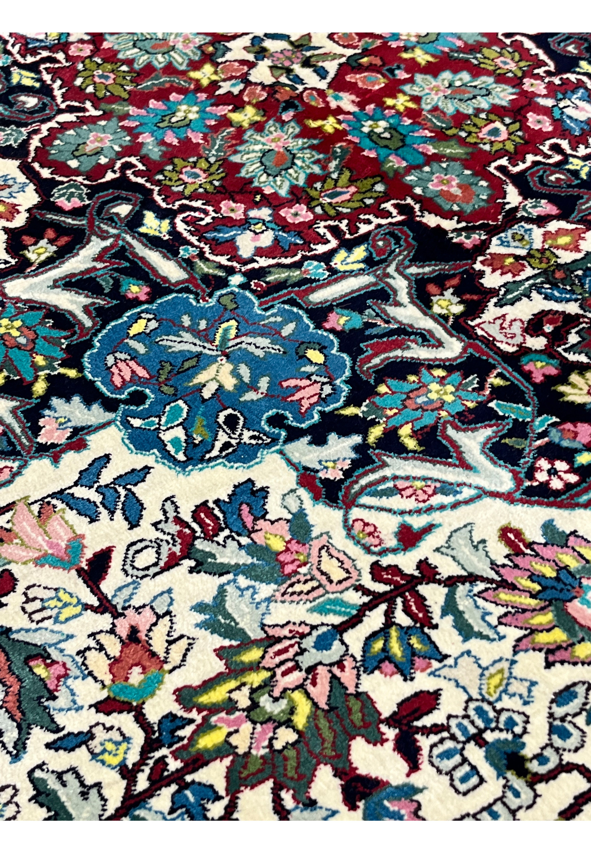 Motif close-up of fine silk oriental rug highlighting curvilinear floral sprays in pastel blue, pink, yellow, and deep red