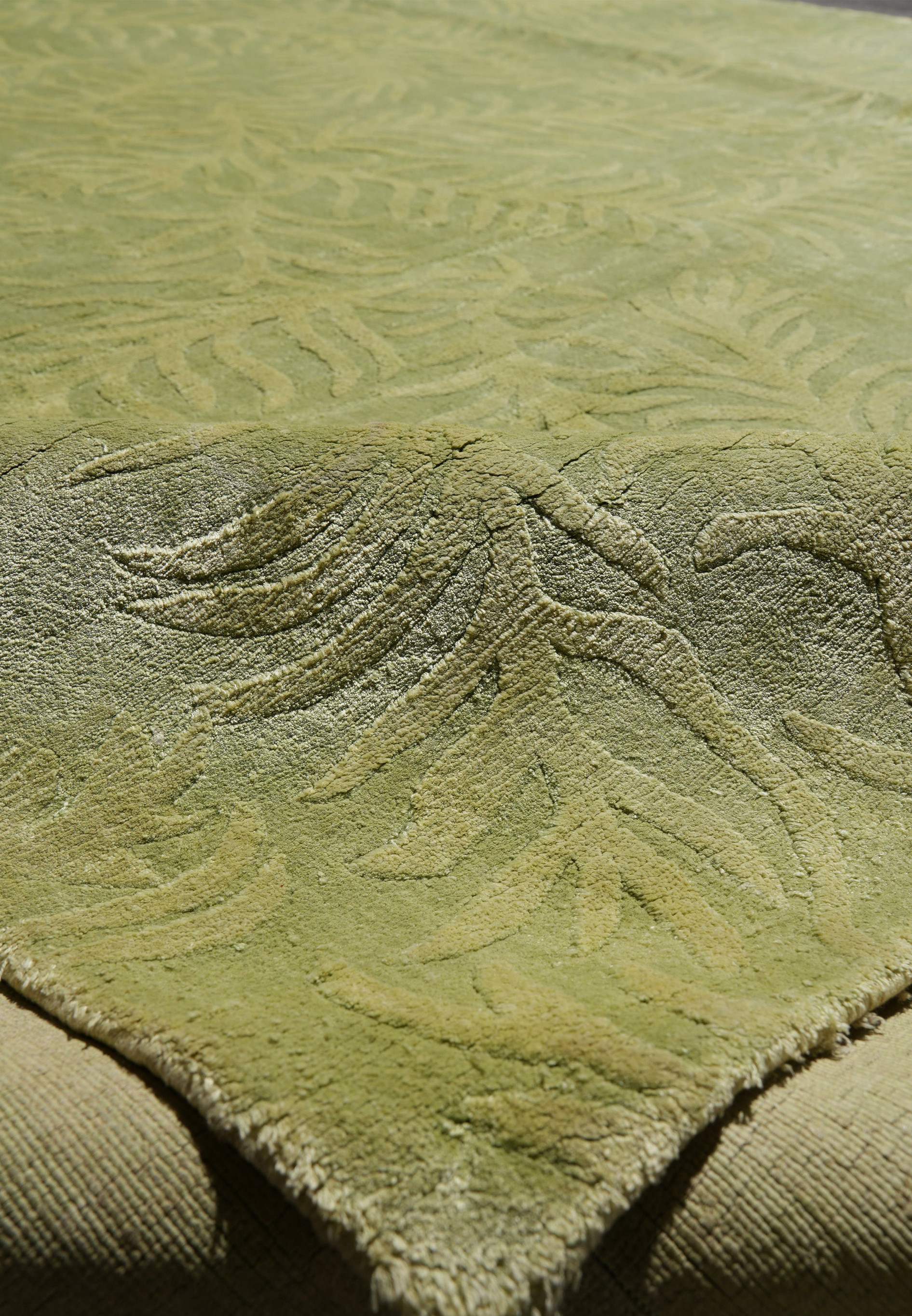 Edge close-up showing clean finishing and the seamless borderless design of this modern wool and silk green rug.