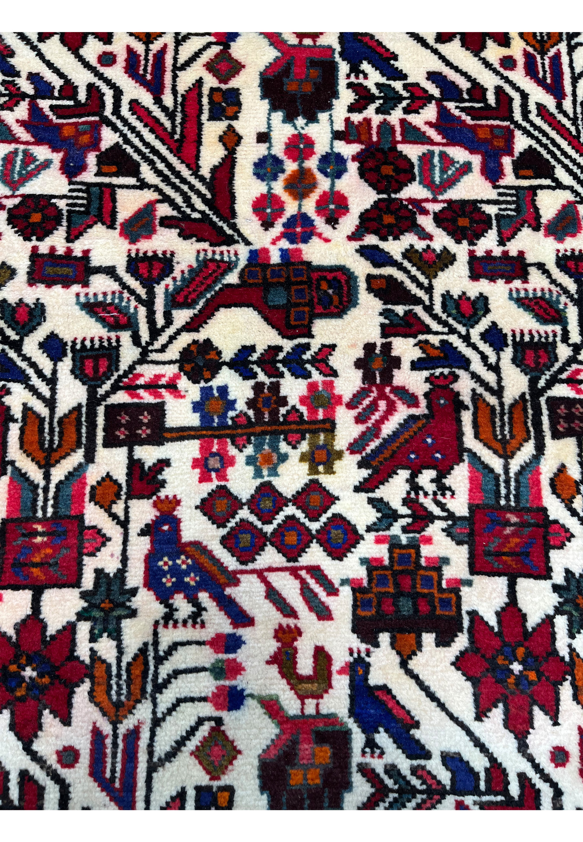 Close-up of Persian Rudbar rug highlighting stylized trees, birds, floral motifs, ivory ground, and vibrant reds, blues, and earthy accents.