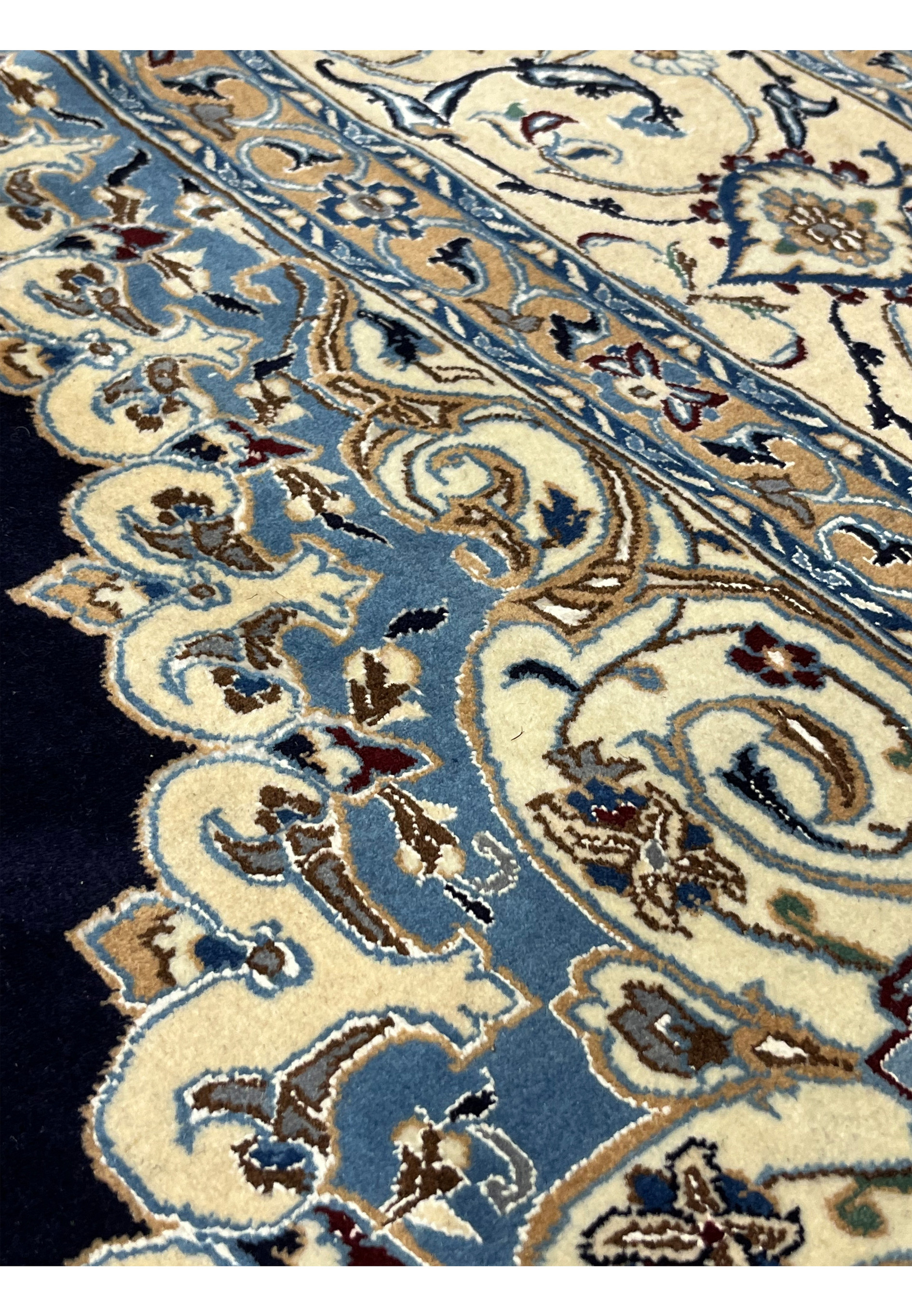 Color detail close-up of a Persian Nain 6 LA rug showing deep navy field, ivory floral elements, light blue accents, and subtle beige highlights