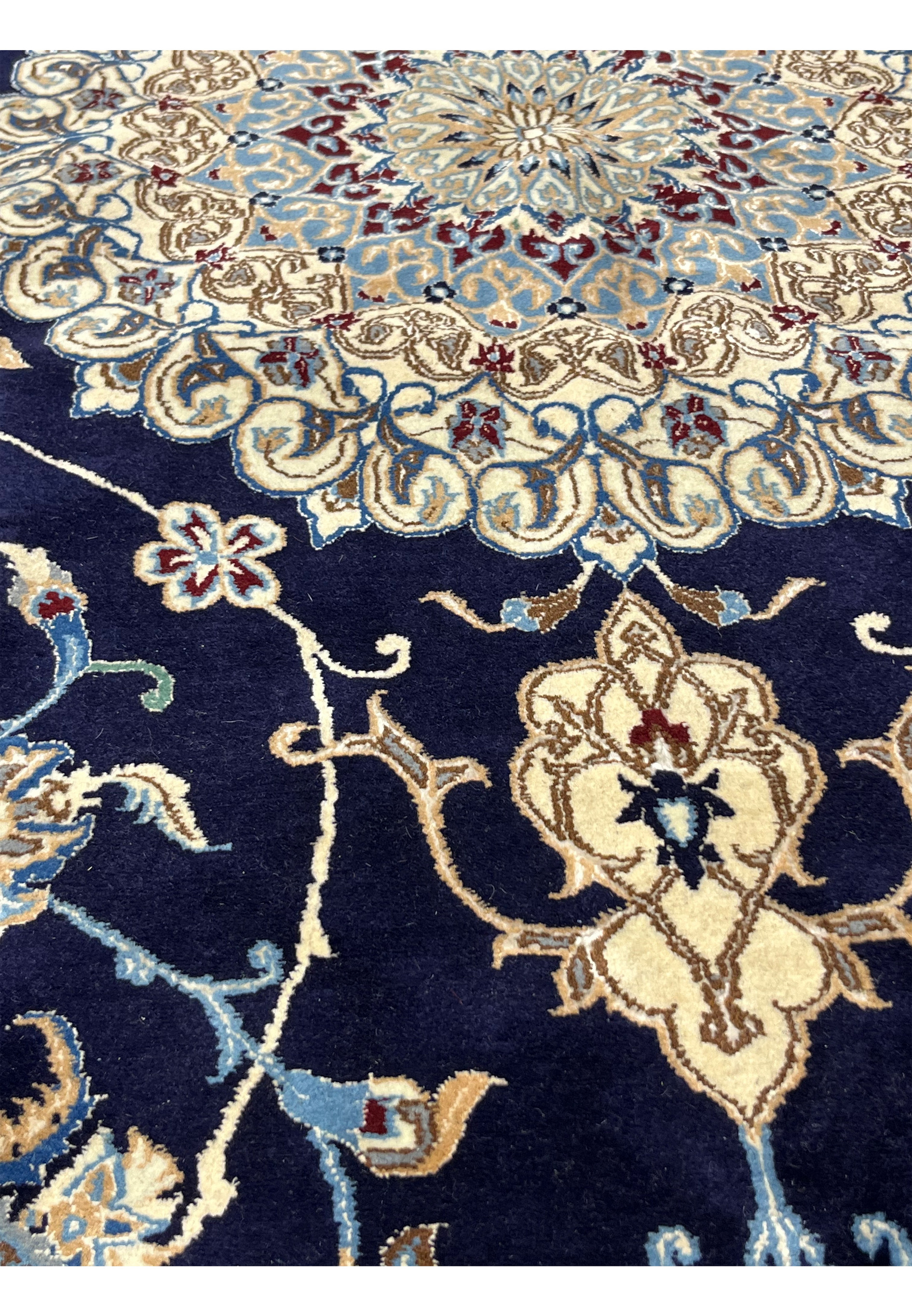 Close-up of Persian Nain 6 LA rug pattern revealing silk-accented floral scrolls, precise knotting, and soft contrast between navy blue and ivory tones