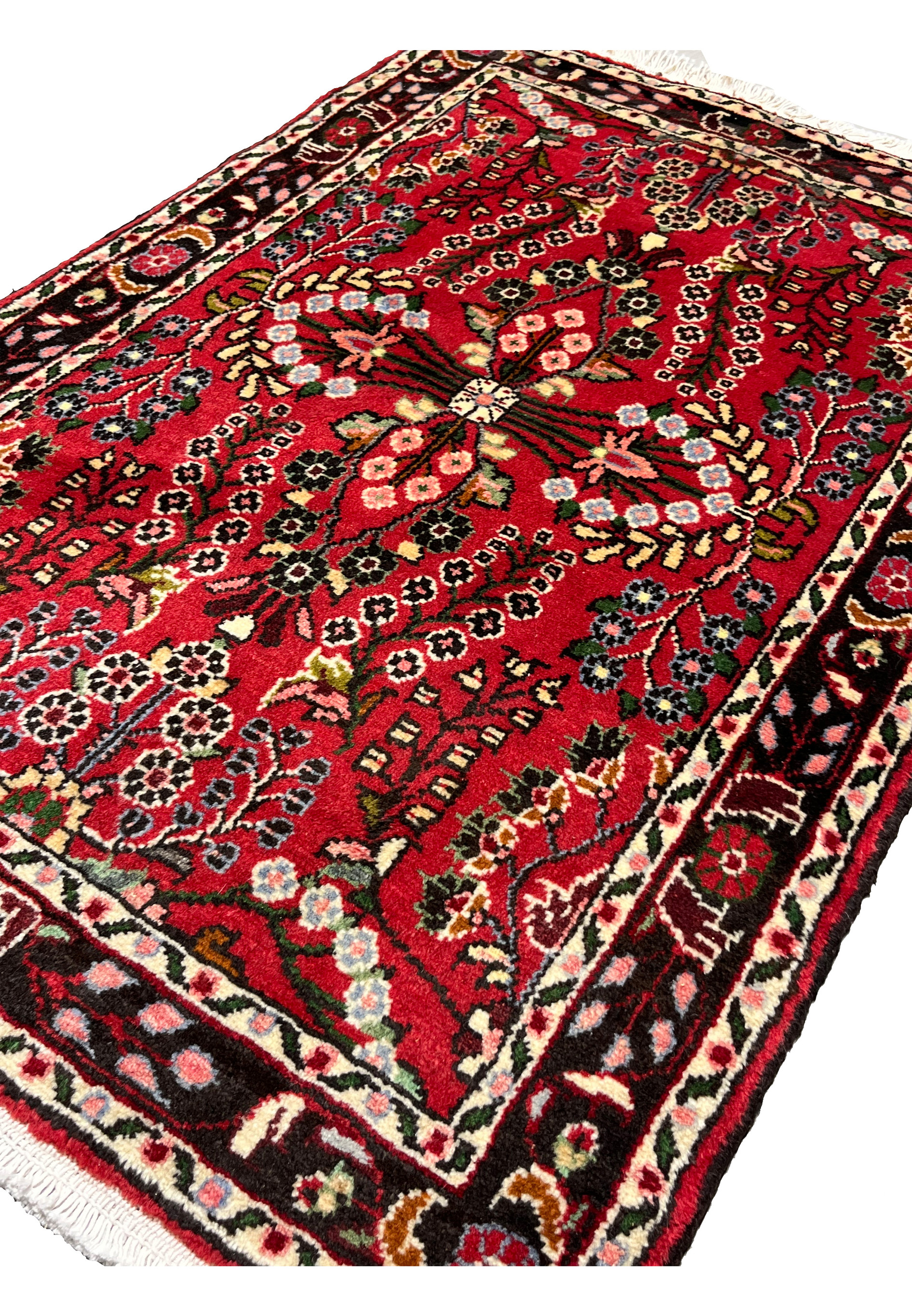 Angled perspective of a Persian Darjazin rug emphasizing pile height, dense knotting, vivid crimson tones, and dimensional floral motifs across the surface