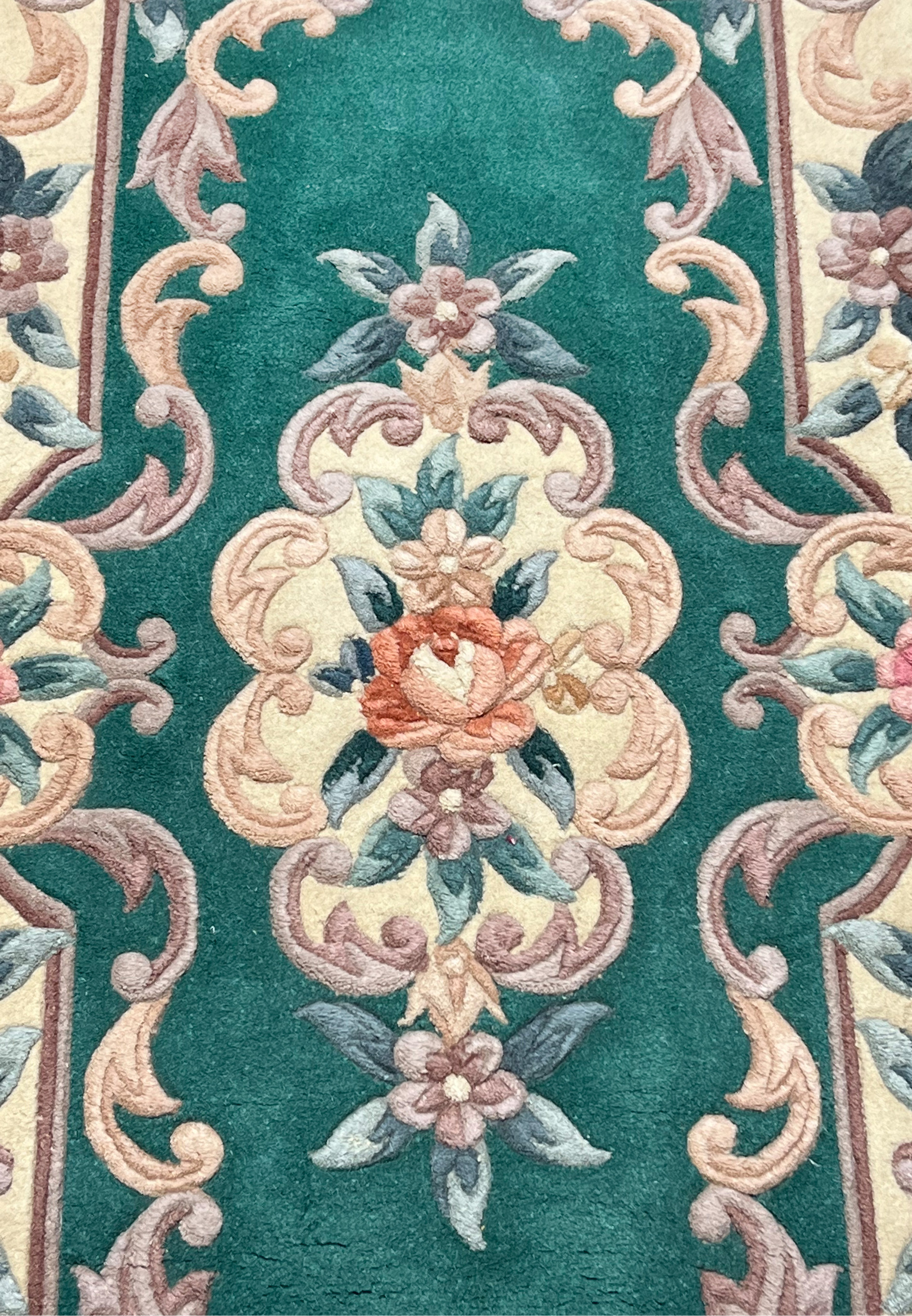 Close view of central floral motif on Aubusson Art Deco rug highlighting raised scrollwork texture and soft blush, sage, and ivory colors