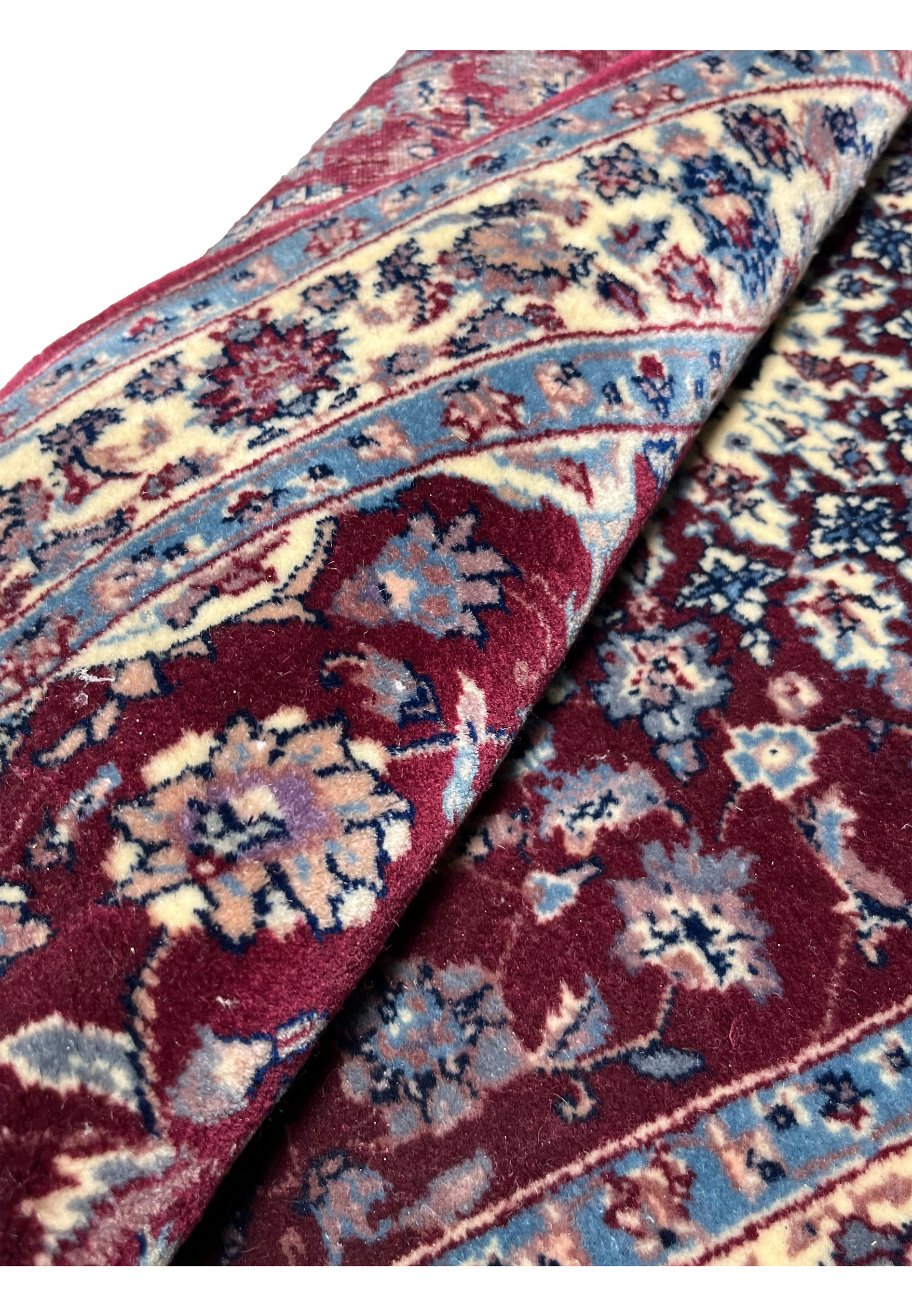 Rolled view of a Persian Tabriz rug demonstrating flexible wool pile, dense hand-knotting, and layered construction typical of fine Tabriz weaving