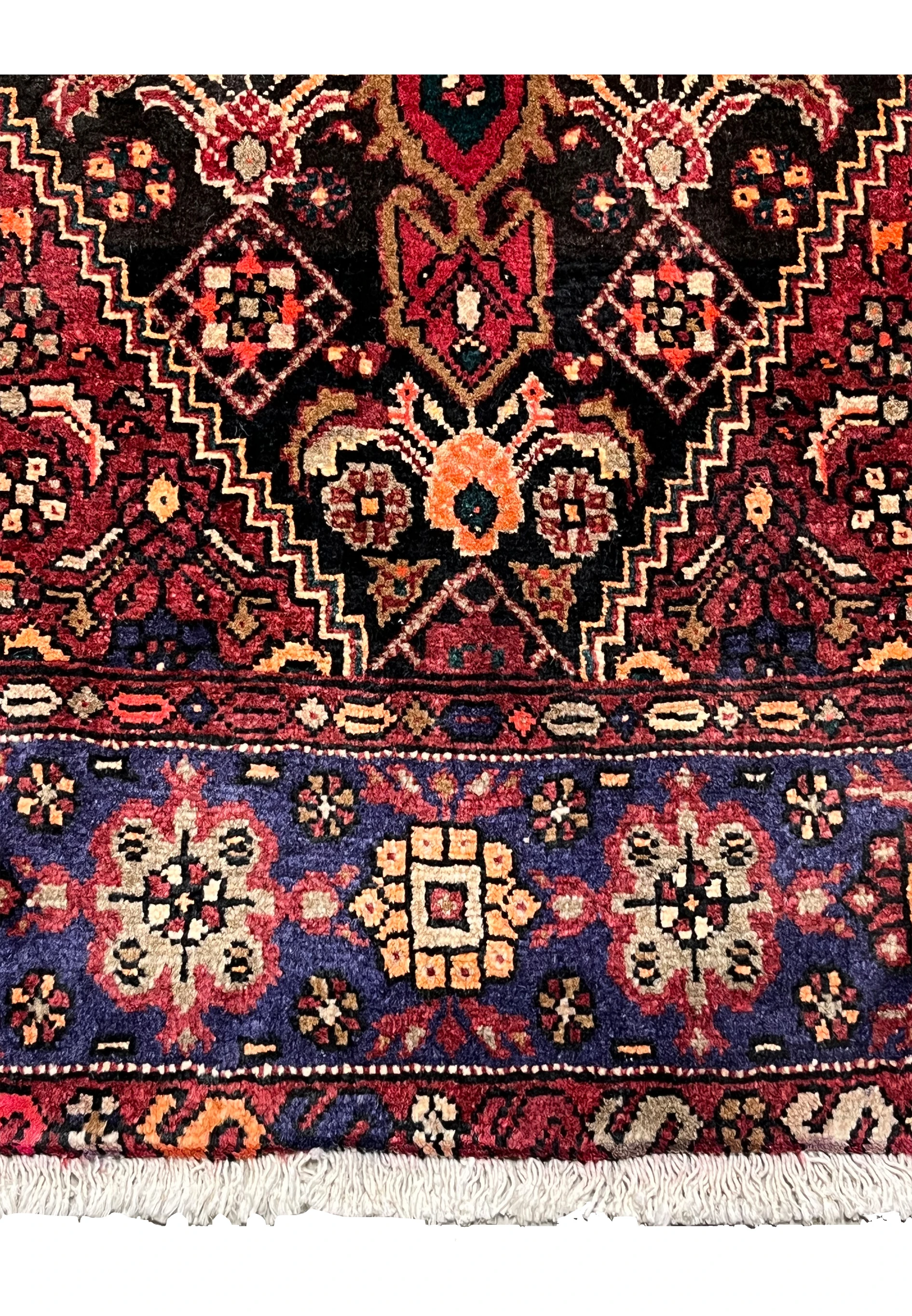 Lower border detail of a Persian Gholtogh rug displaying geometric motifs, navy framing, ivory accents, and consistent knot structure