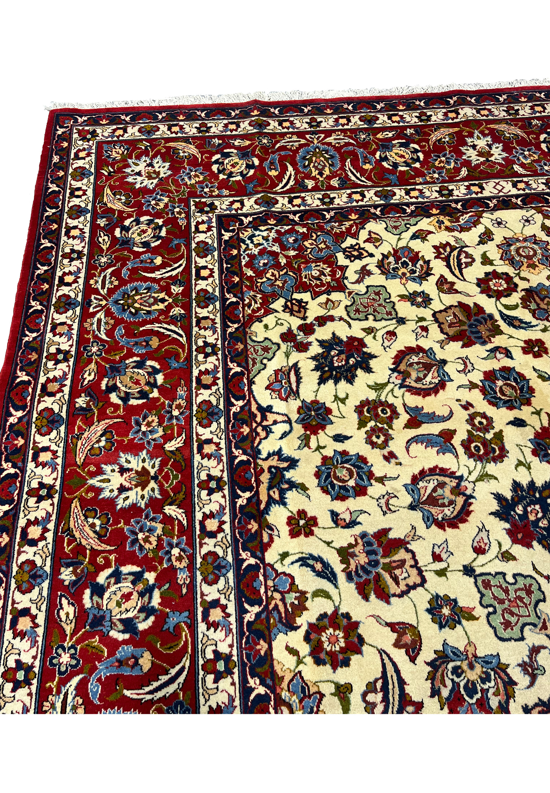 Upper border closeup of a Persian Isfahan rug featuring deep red tones, scrolling floral vines, navy accents, and elegant silk highlights