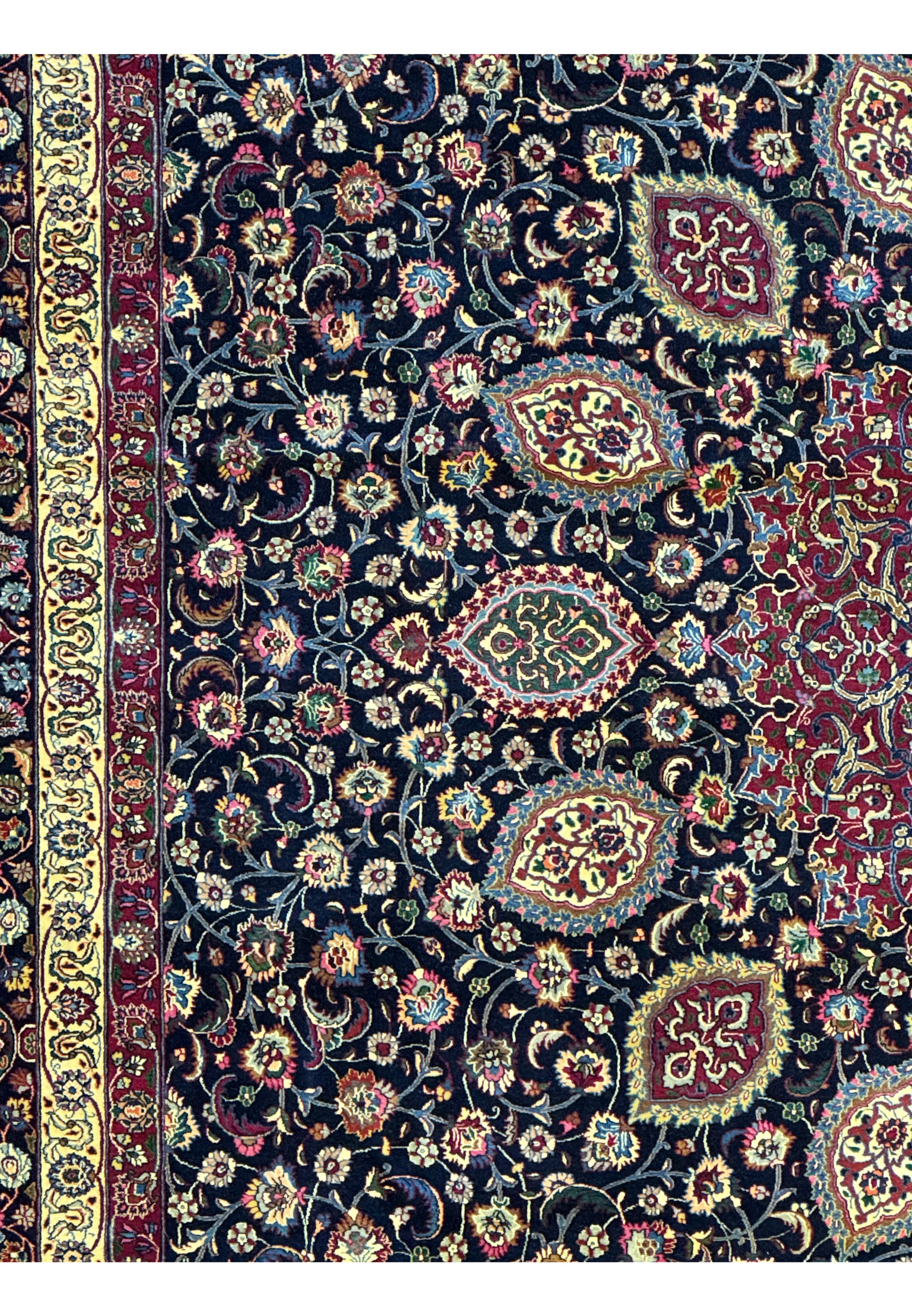 Midfield close-up of Persian Mashad rug highlighting dense floral composition, curved vine motifs, vibrant colors, and luxurious silk detailing