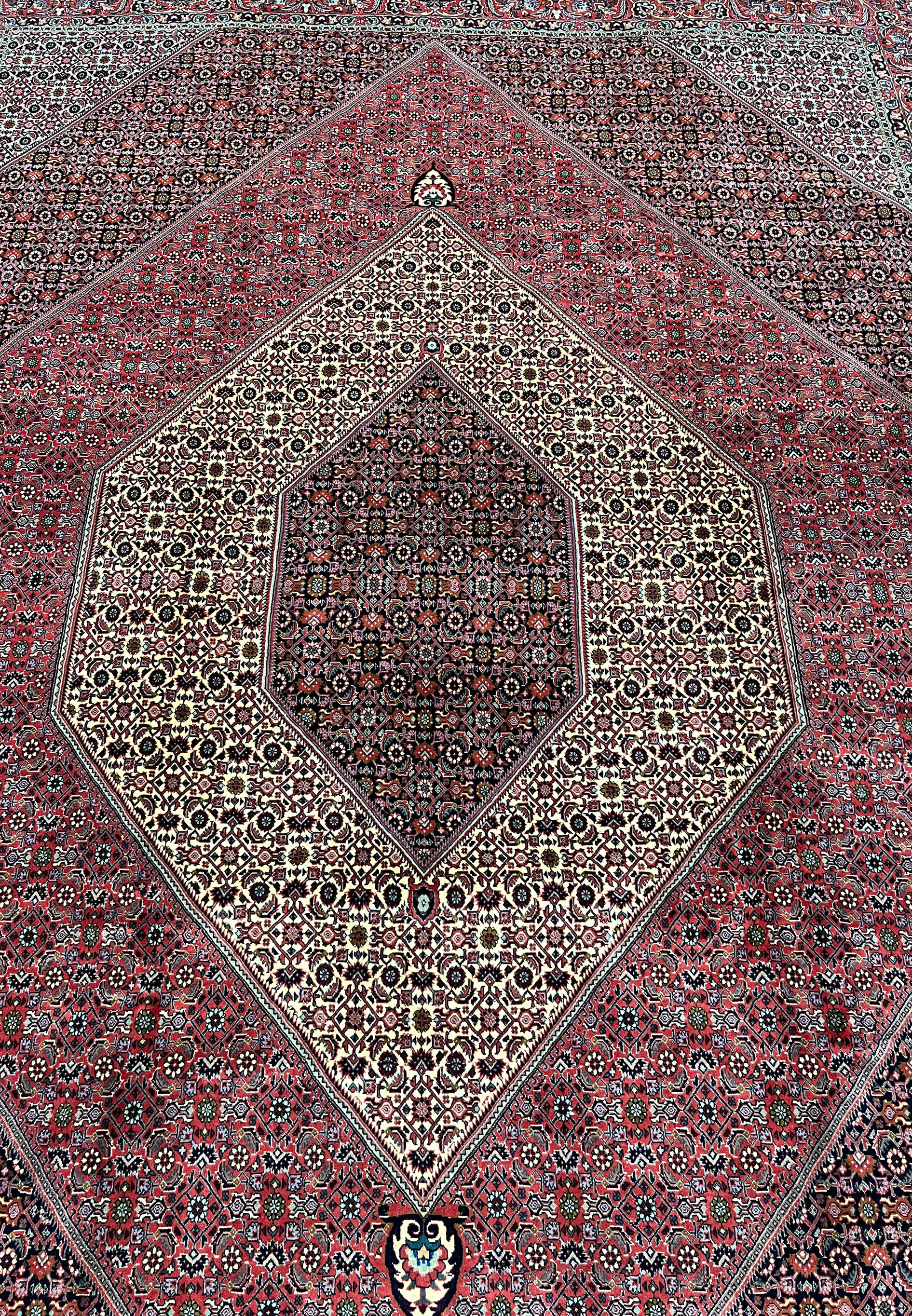 Central field detail of a Persian Bijar iron rug showing dense geometric elements, tight knotting, ivory accents, and rich brick red background